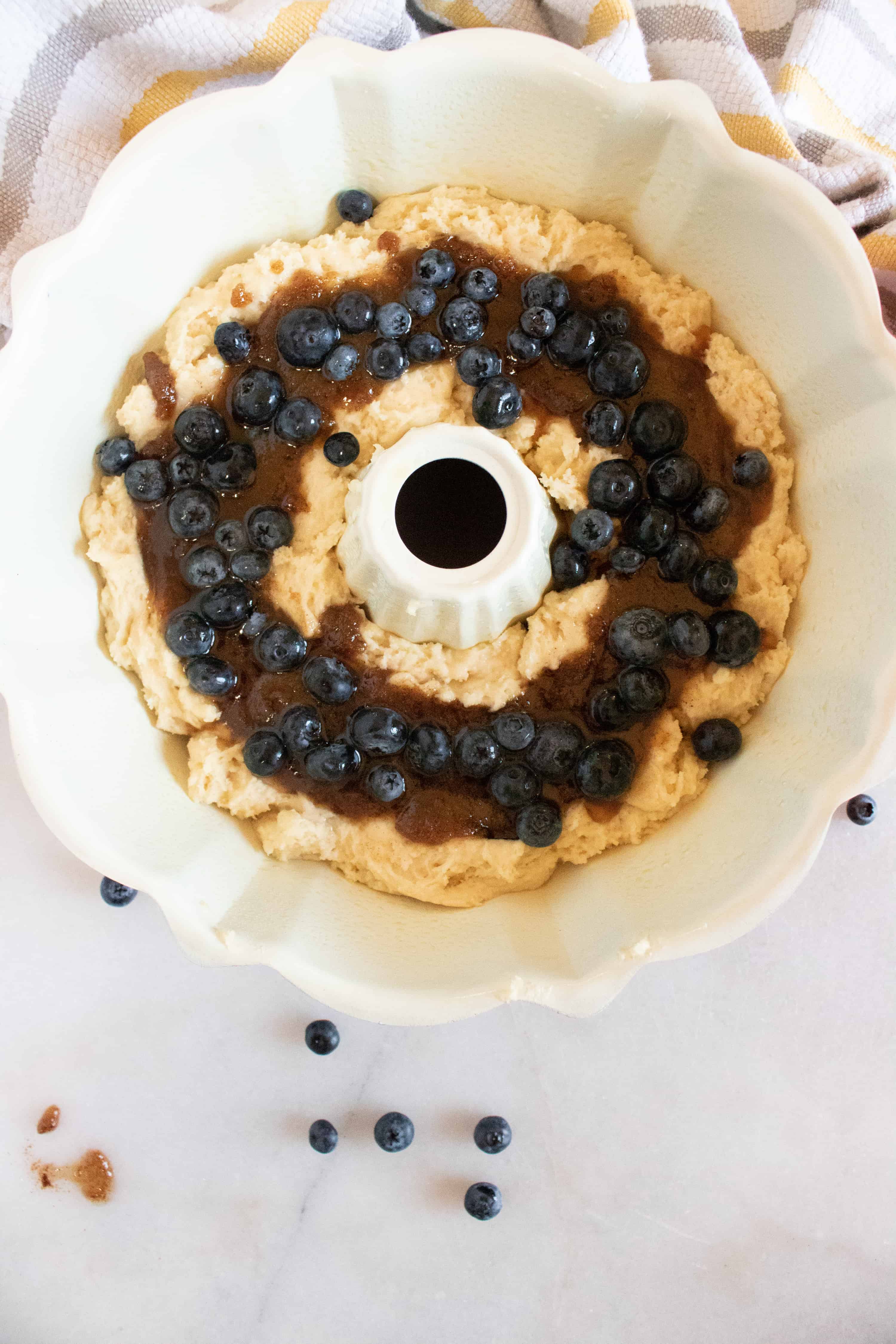 white bundt pan with coffee cake batter and blueberries