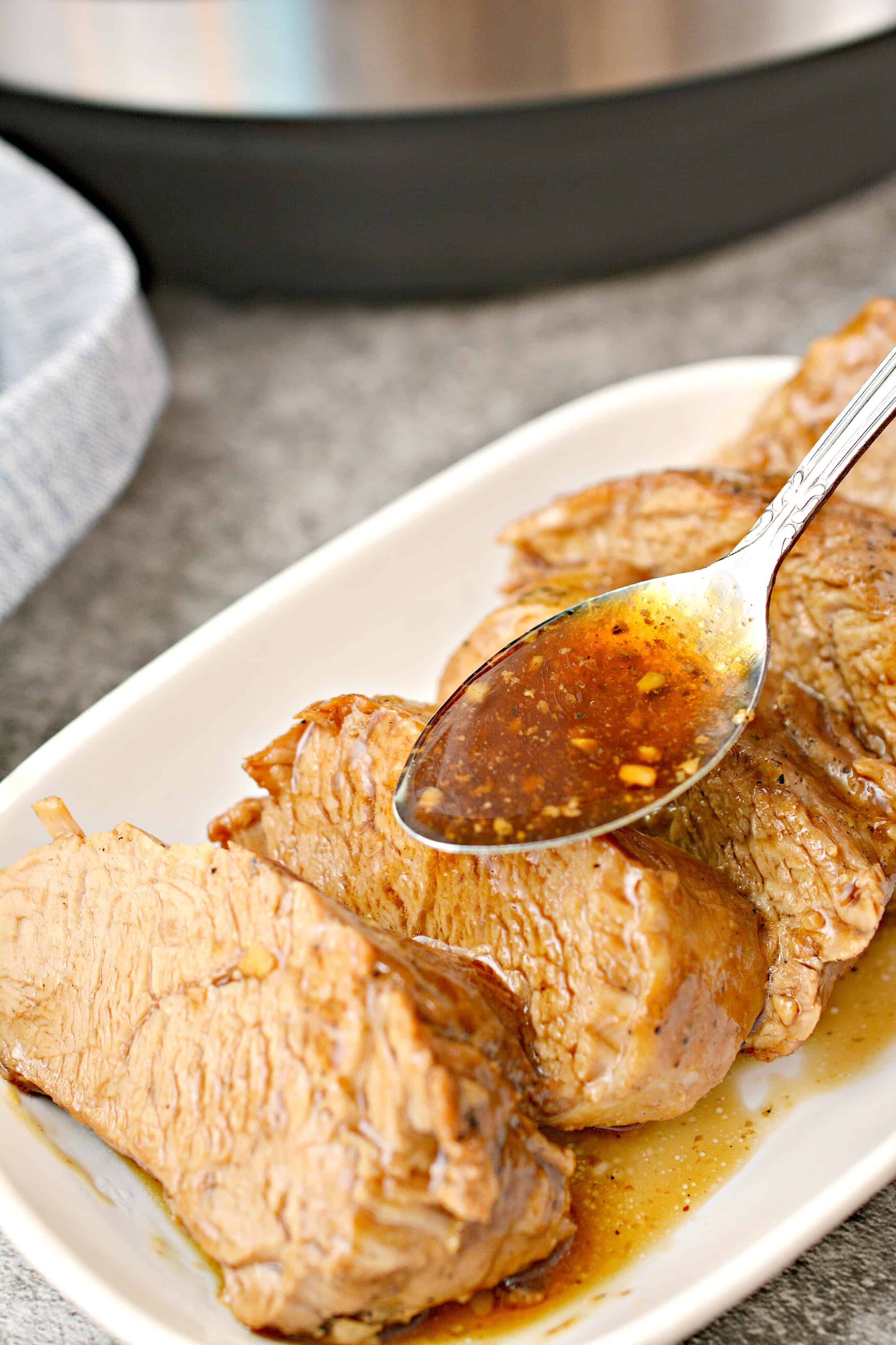 Pouring juices over the top of sliced instant pot pork loin