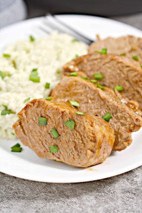 A white plate with instant pot pork loin slices and rice