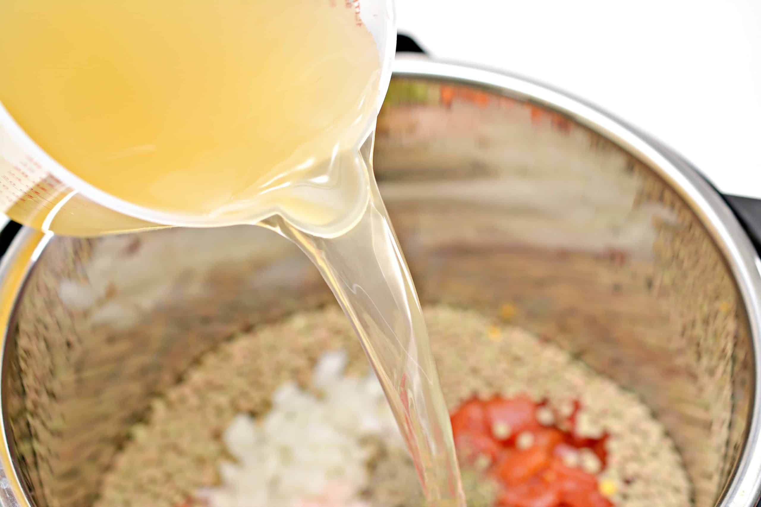 pouring chicken broth in soup
