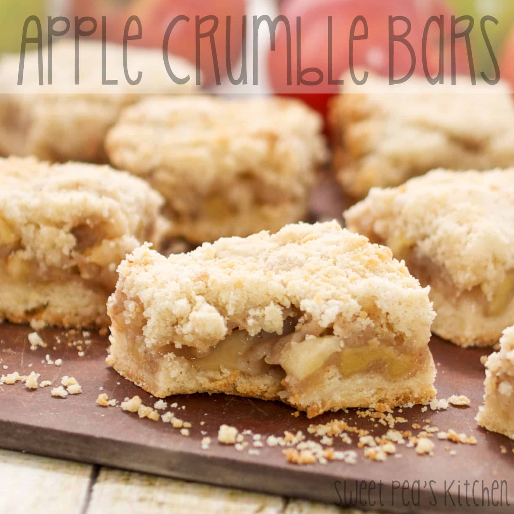 Apple crumble bars on a wooden board with one bite out of the one in front