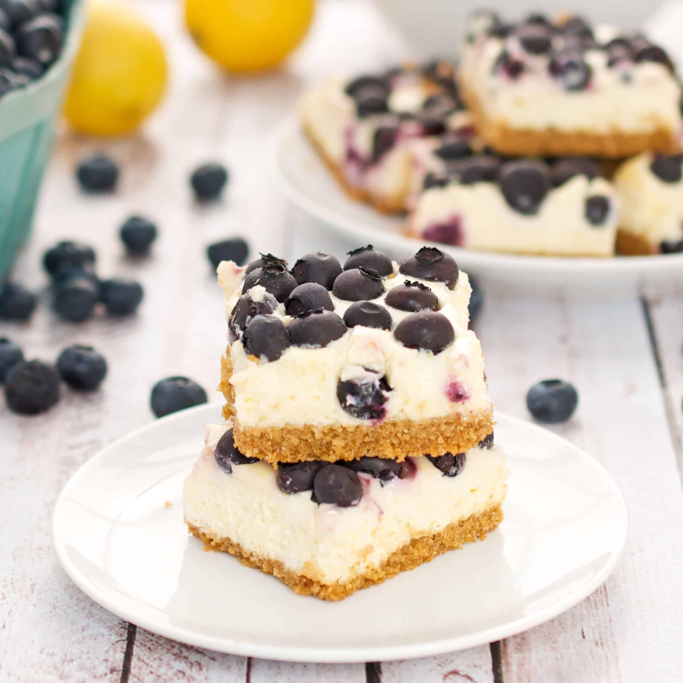 lemon cheesecake bars with bluberries on a white plate