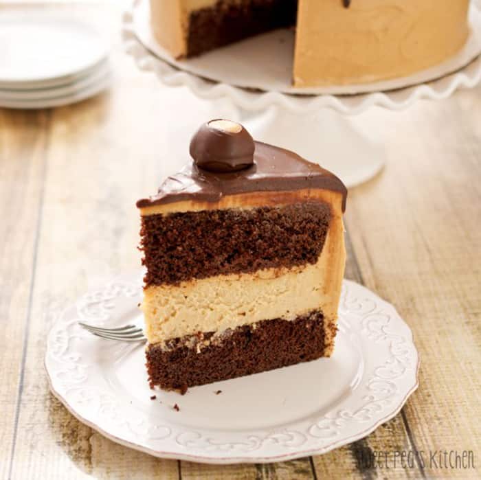 Buckeye Peanut Butter Cheesecake Layer Cake one slice sitting on a white saucer that is on a wooden surface