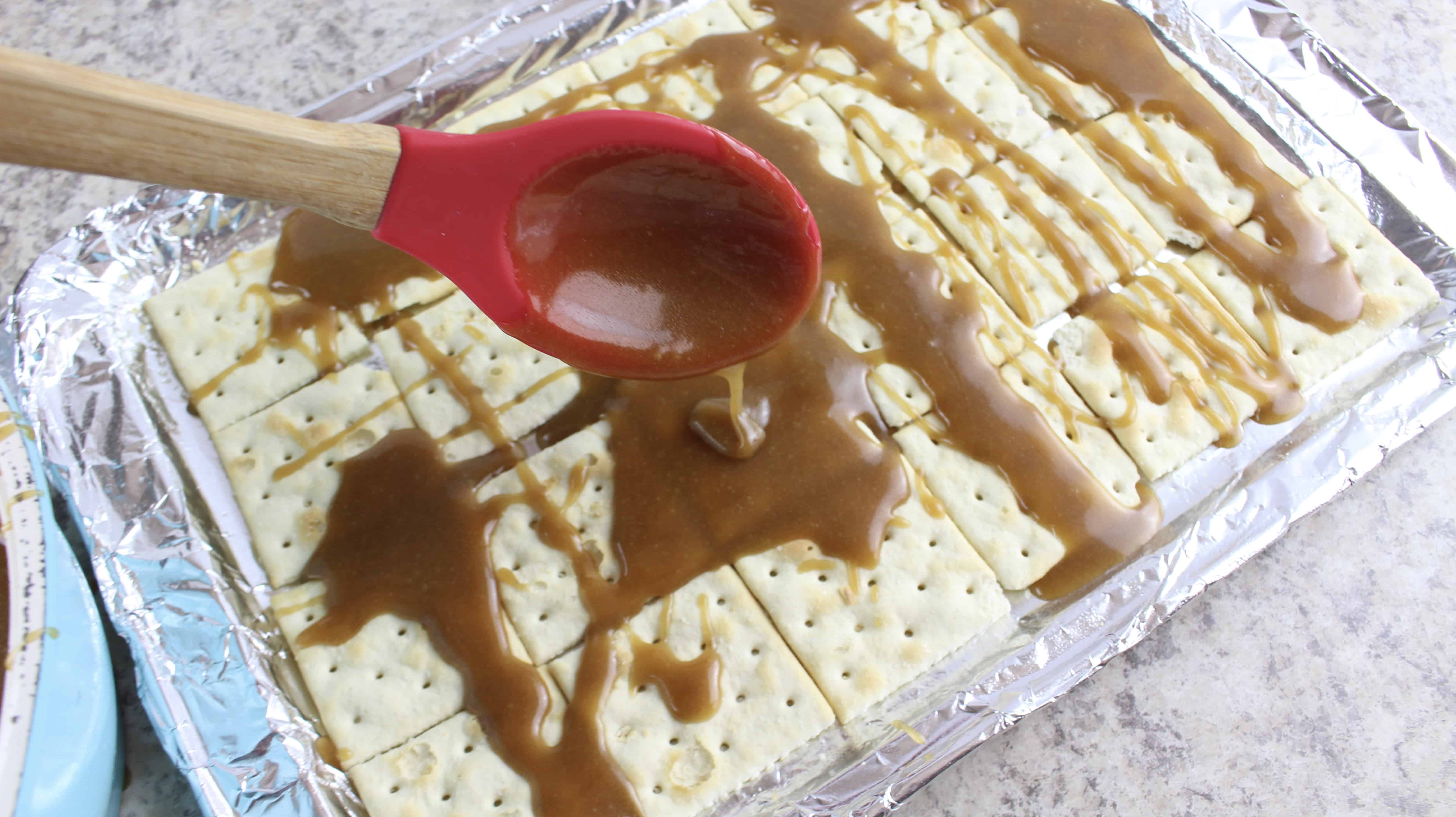 spoon pouring toffee on the crackers