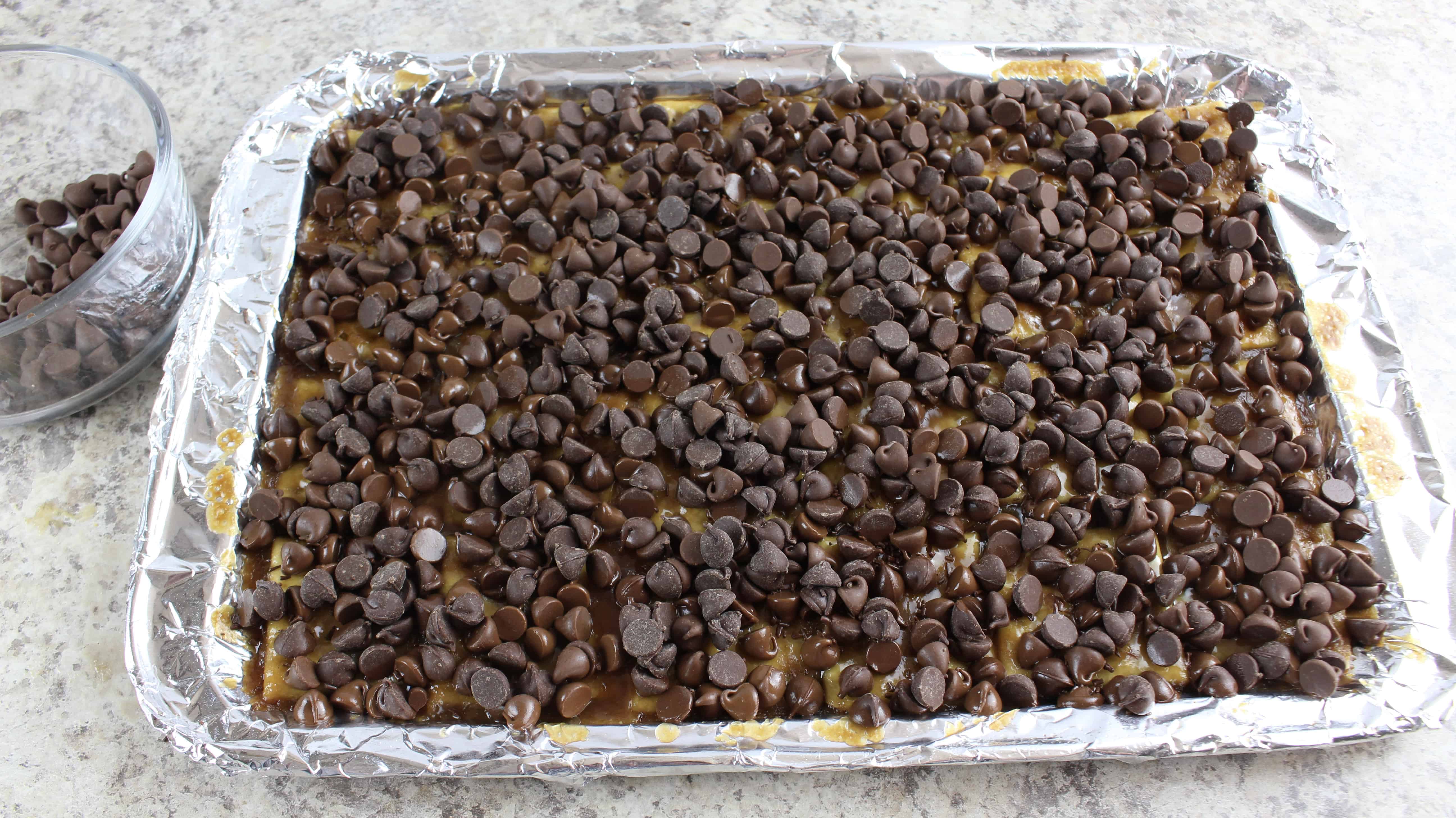 chocolate chips on crackers in a cookie sheet