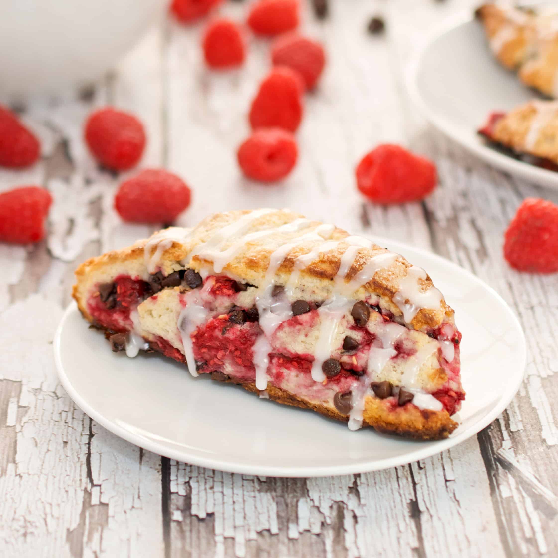 dark chocolate and raspberry scone on a plate with raspberries on the table