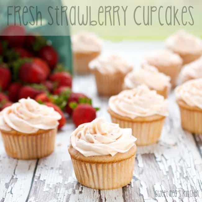 strawberry cupcakes on a board with strawberries in the back. 