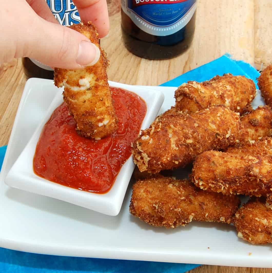 dipping fried mozzarella stick in sauce