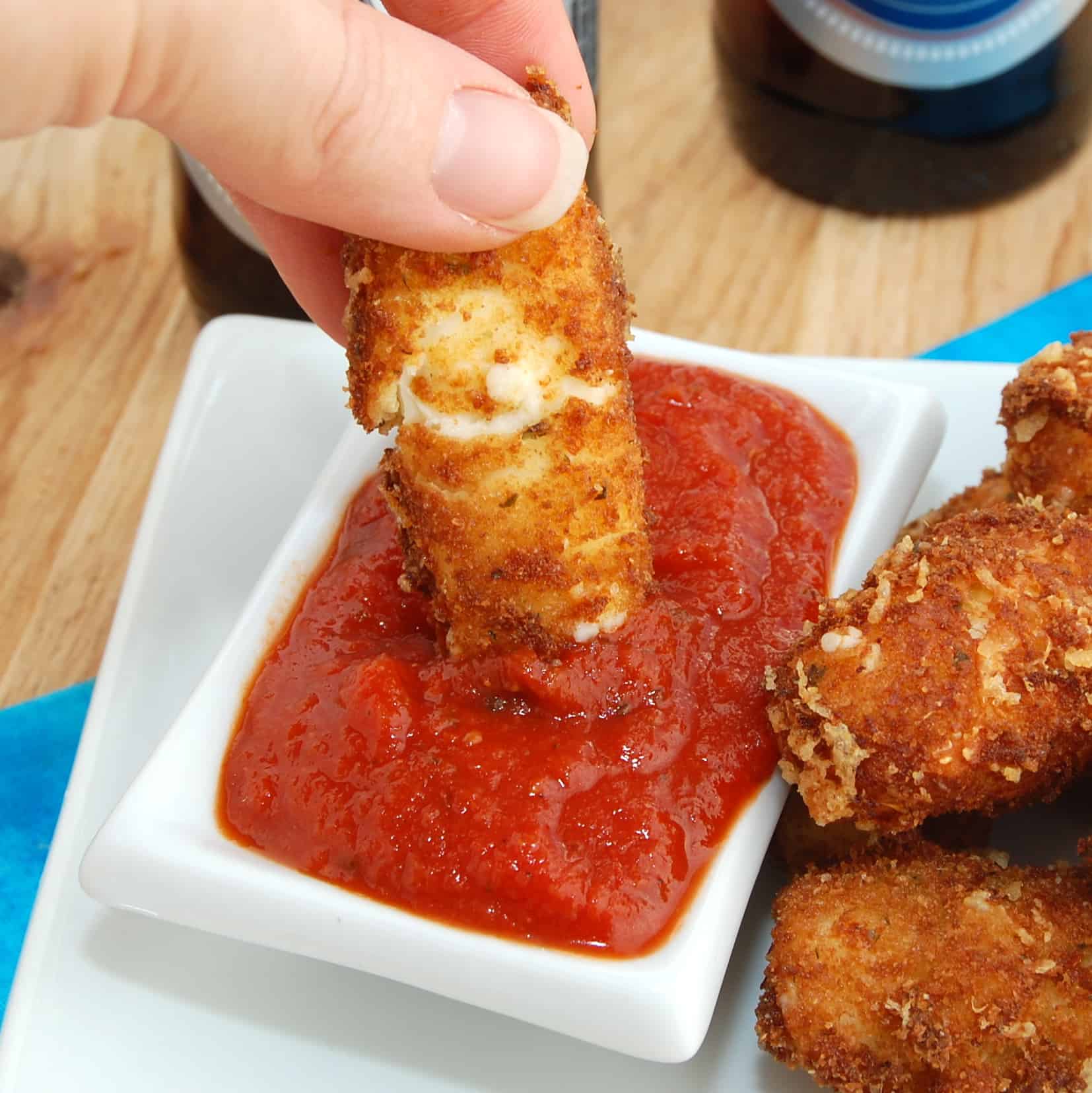 Dipping homemade mozzarella stick in sauce