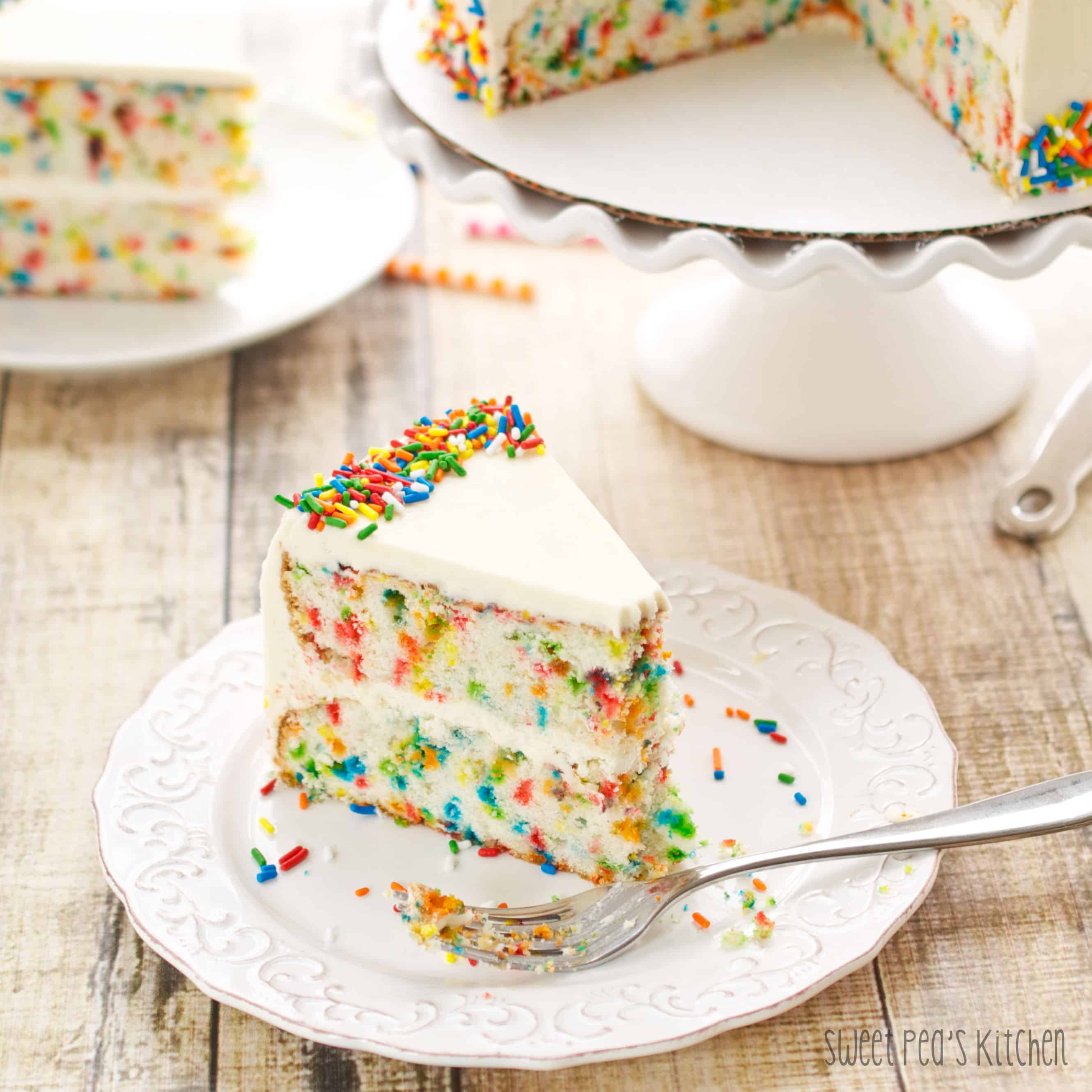 slice of funfetti cake on a white plate with a fork