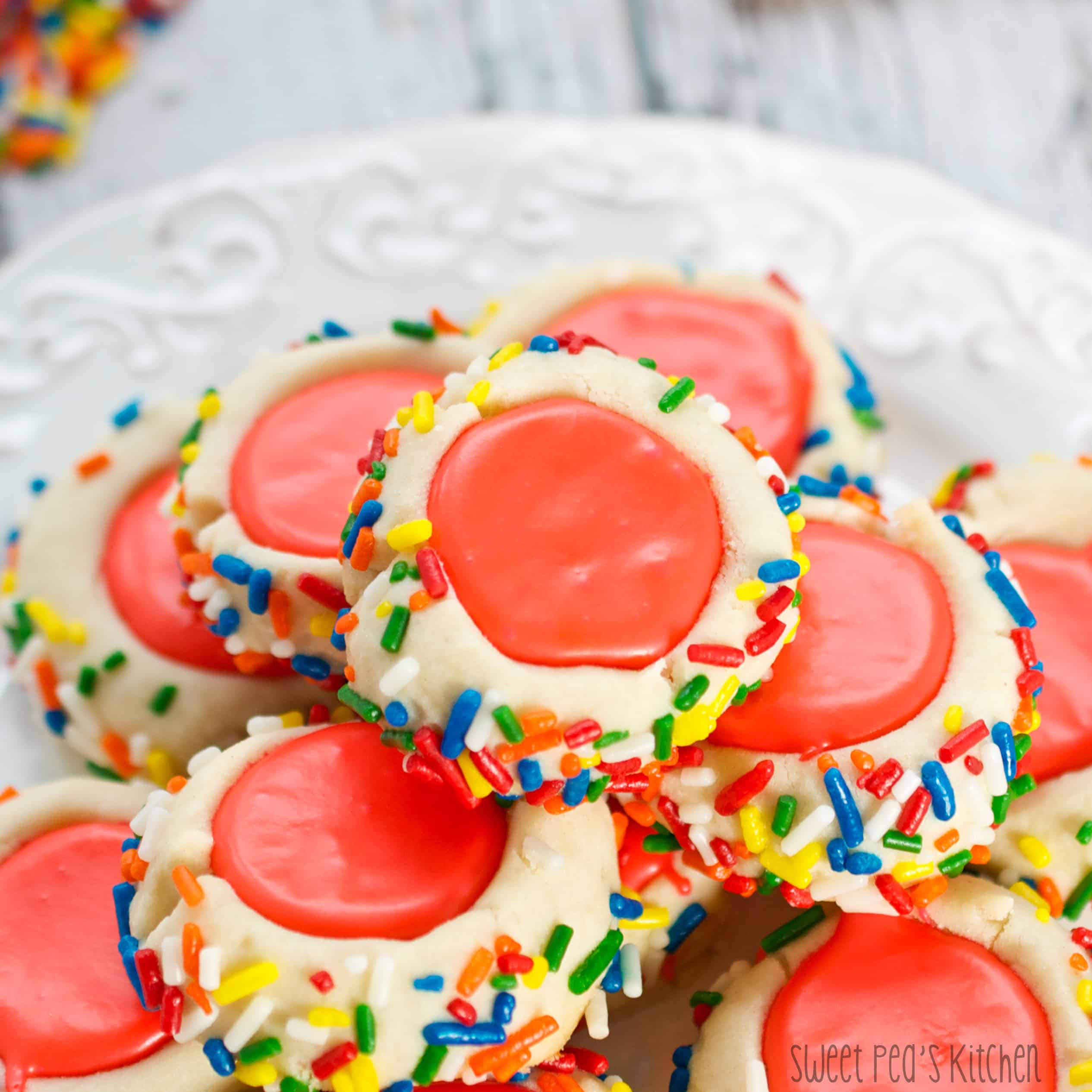 Plate with multiple cooked iced thumbprint cookies with sprinkles