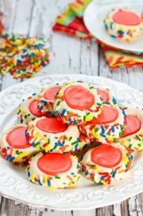 A plate of icing filled thumbprint cookie recipe with red icing and sprinkles