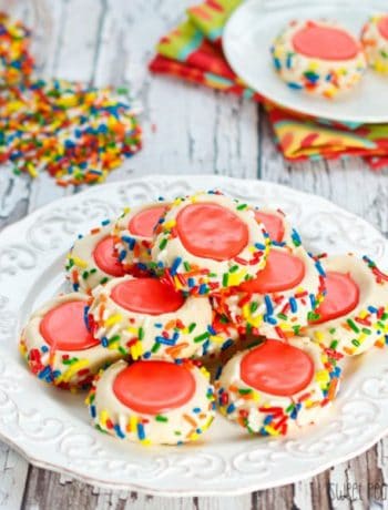 A plate of icing filled thumbprint cookie recipe with red icing and sprinkles