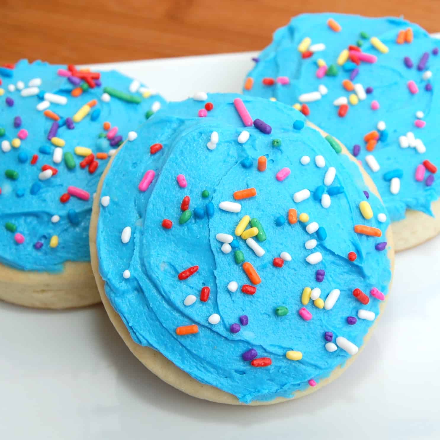 soft lofthouse cookies with blue frosting on a white plate