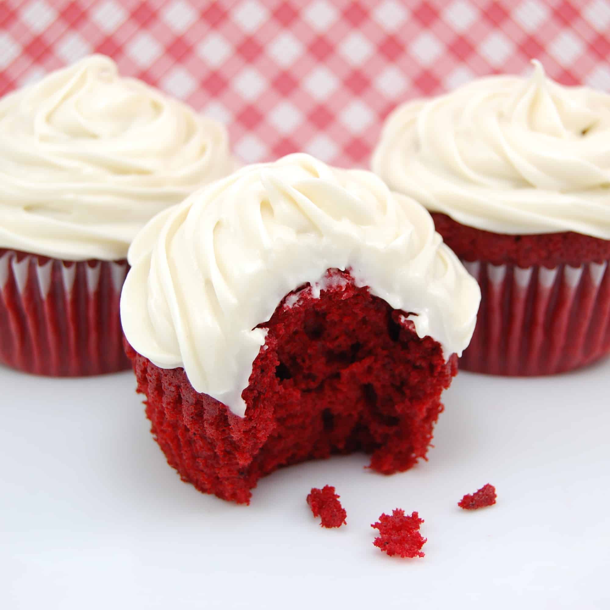 red velvet cupcakes on a white counter with a checked background