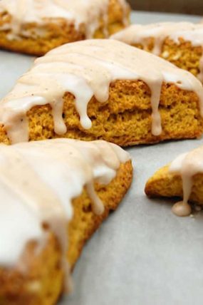 Pumpkin Scones prepared sitting on parchment paper topped with glaze