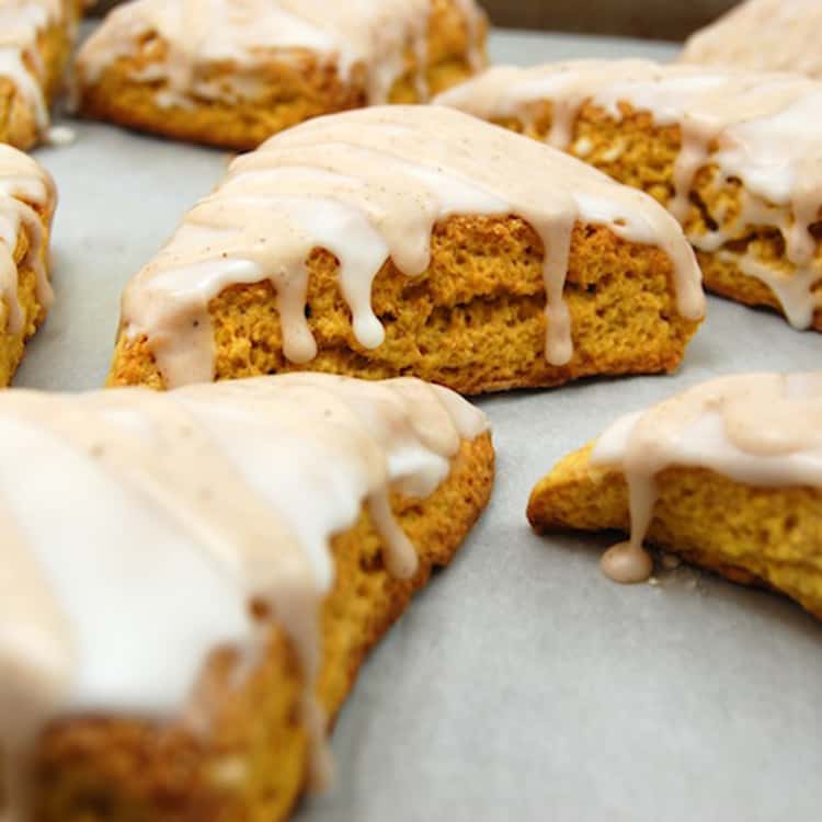 Pumpkin Scones prepared sitting on parchment paper topped with glaze