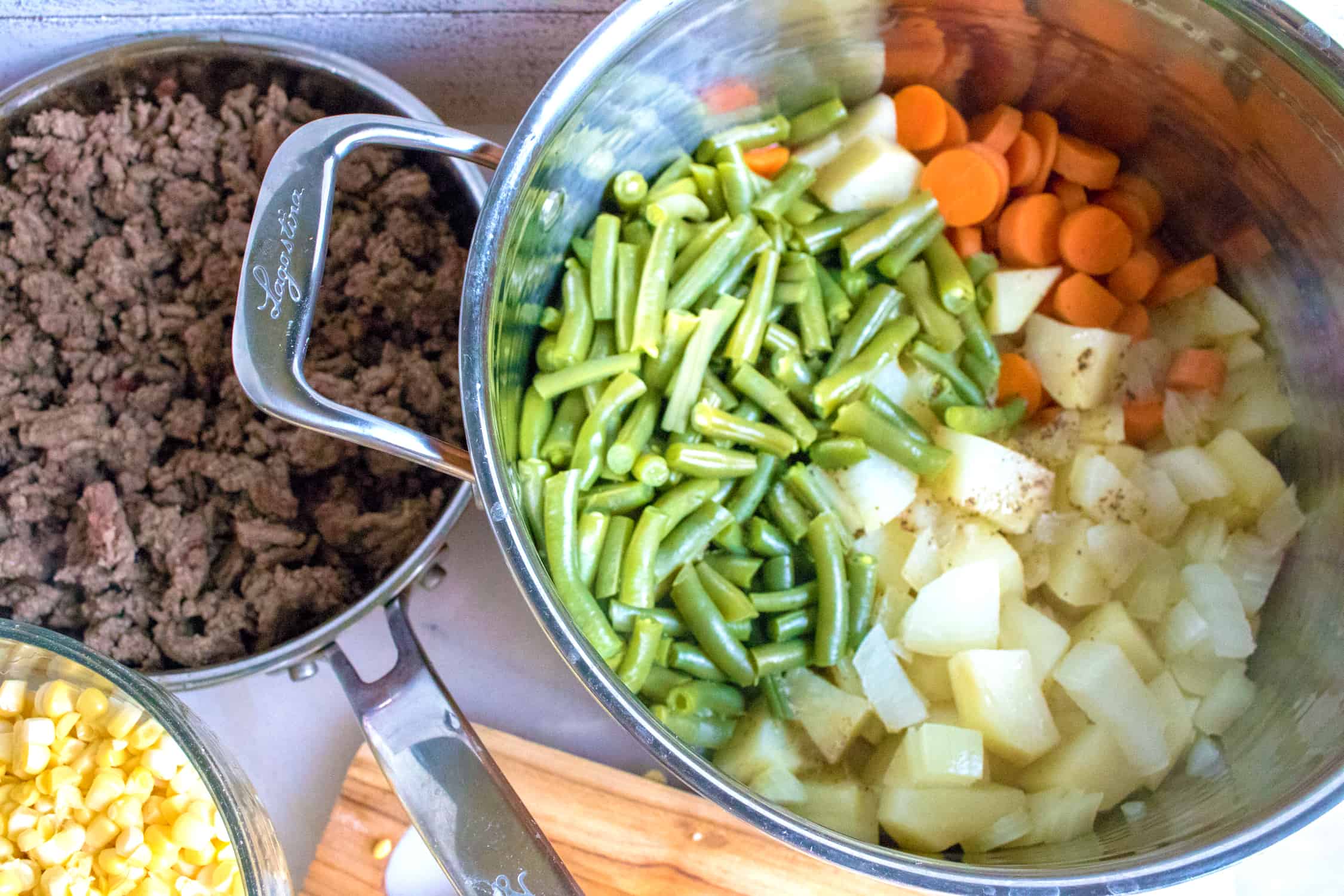 cooked veggies in a pot with hamburger and corn in seperate pots