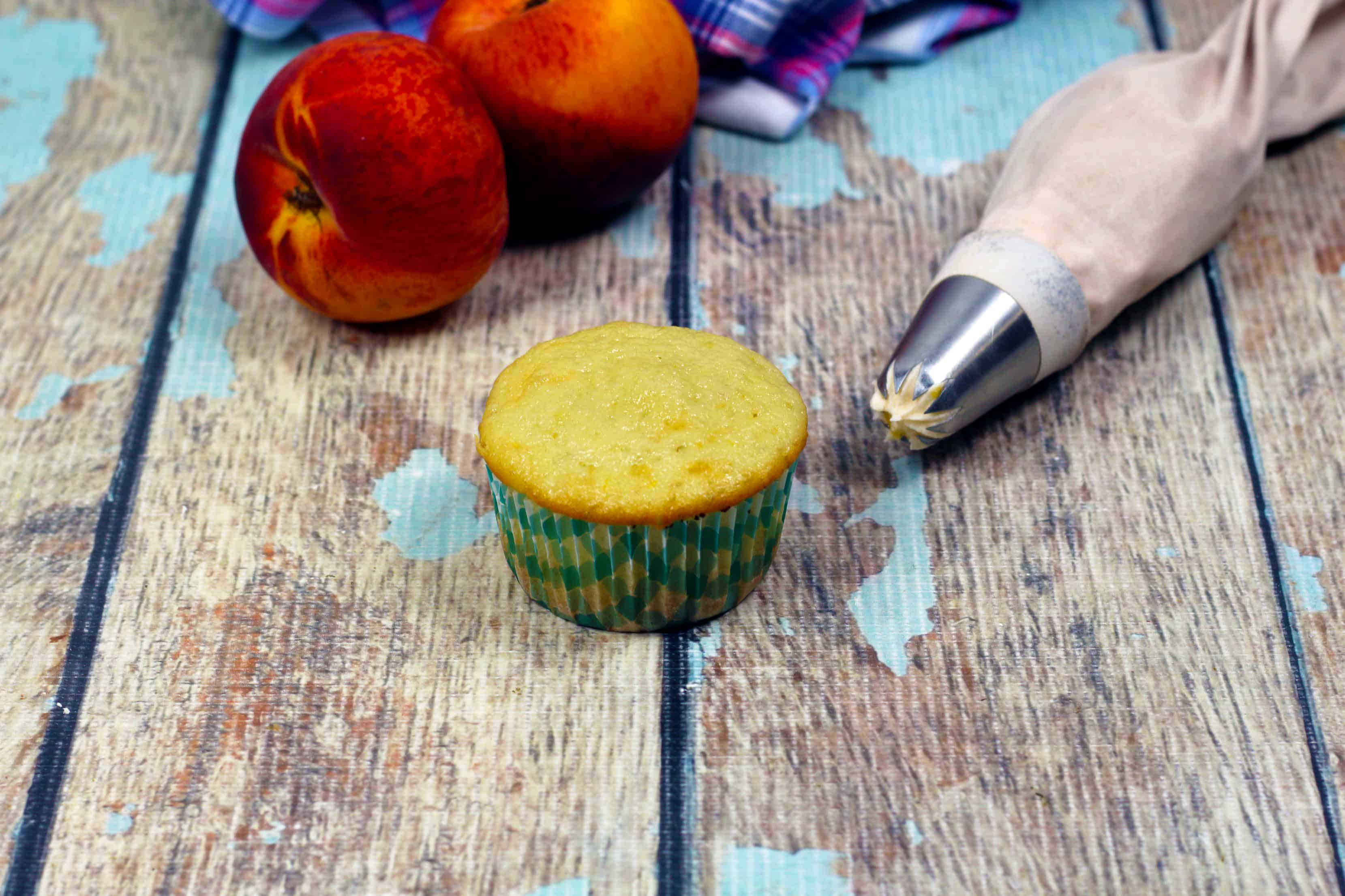 peaches, cupcakes and patry bag on a table