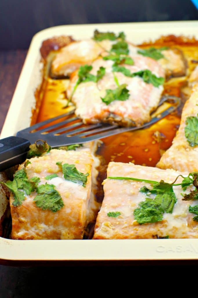 Cooked frozen salmon fillets on a sheet pan with one being left off