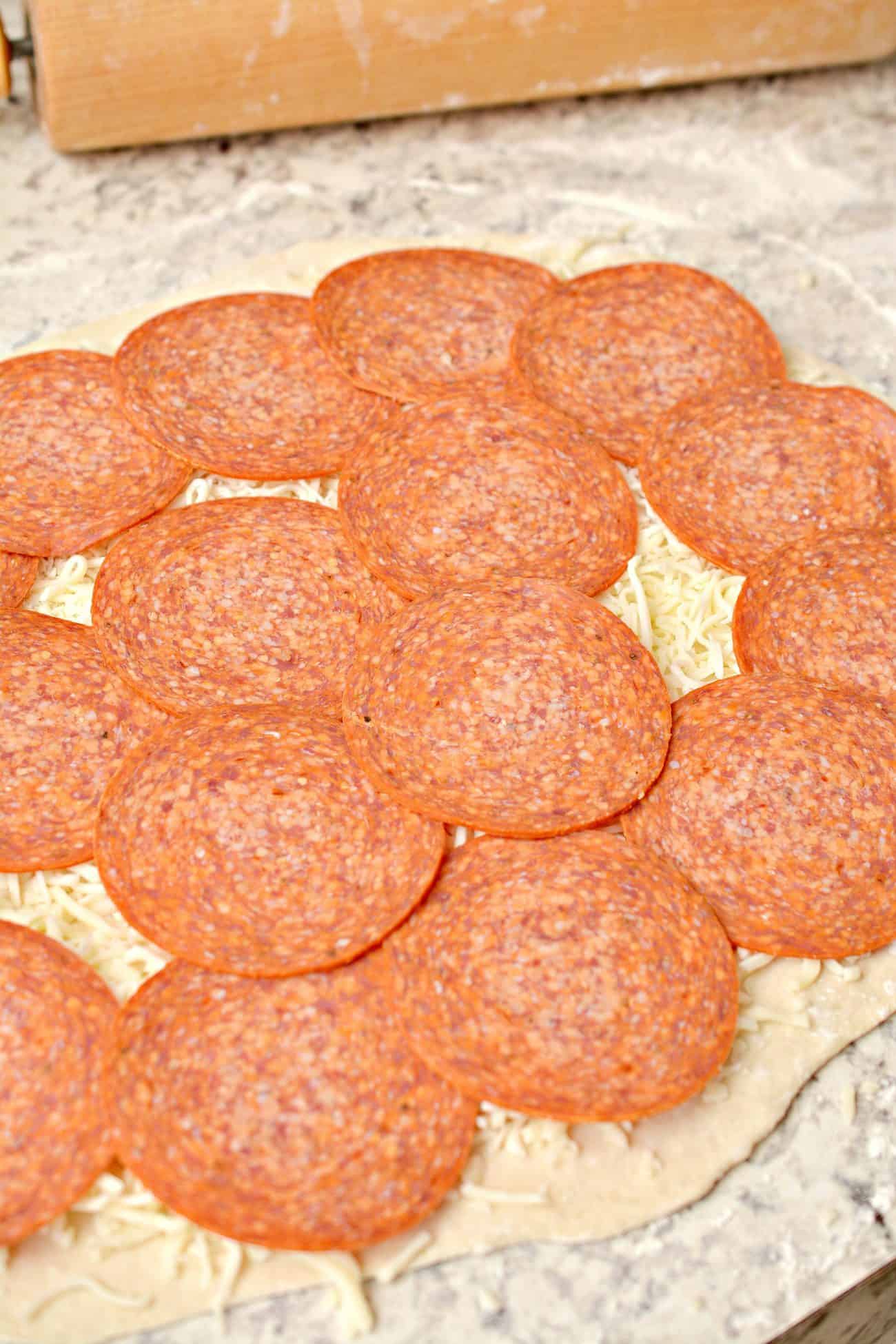 Place a layer of pepperoni slices on top of the cheese.