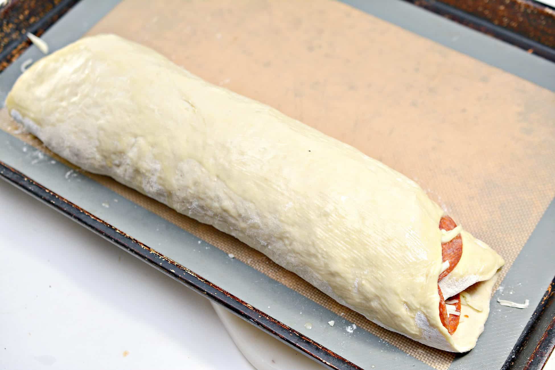 Starting at one end, roll the dough into a log with the cheese and pepperoni on the inside.