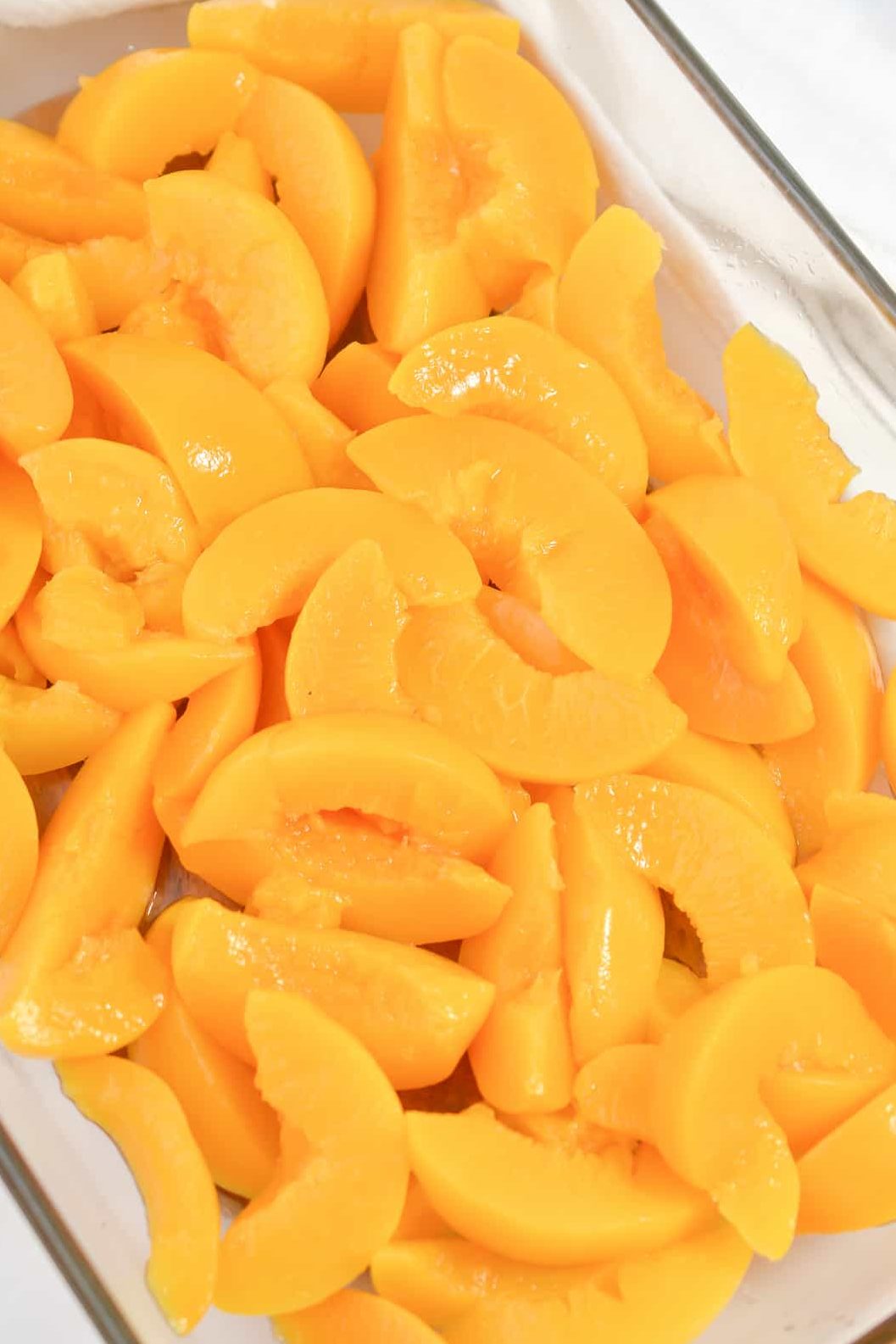 Layer the sliced peaches on the bottom of a well-greased 9x13 baking dish.