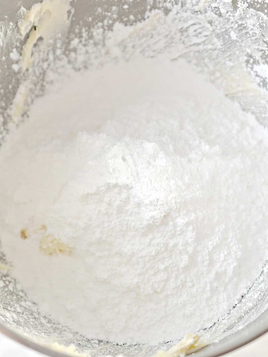 Add 1 tsp vanilla, 4 cups powdered sugar, and 2 tbsp whipping cream to the mixing bowl, and beat on high until creamy and fluffy.