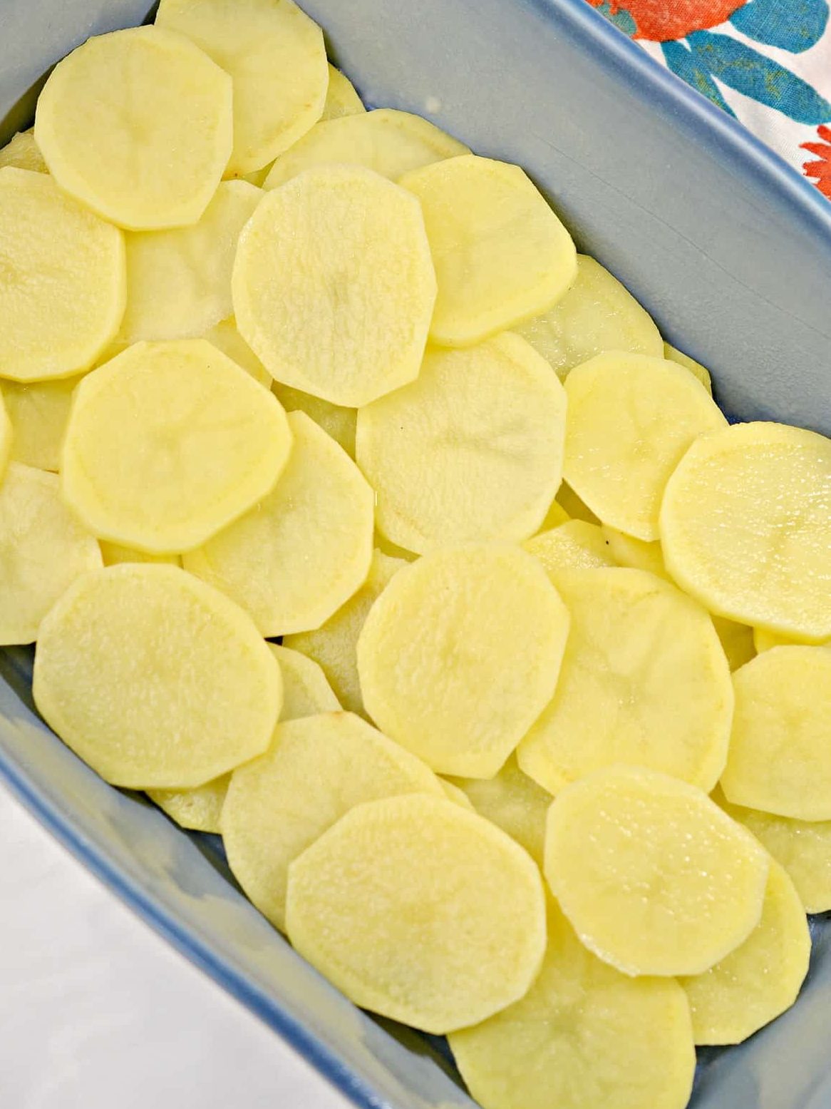 Layer the sliced potatoes on the bottom of a 9x13 baking dish.