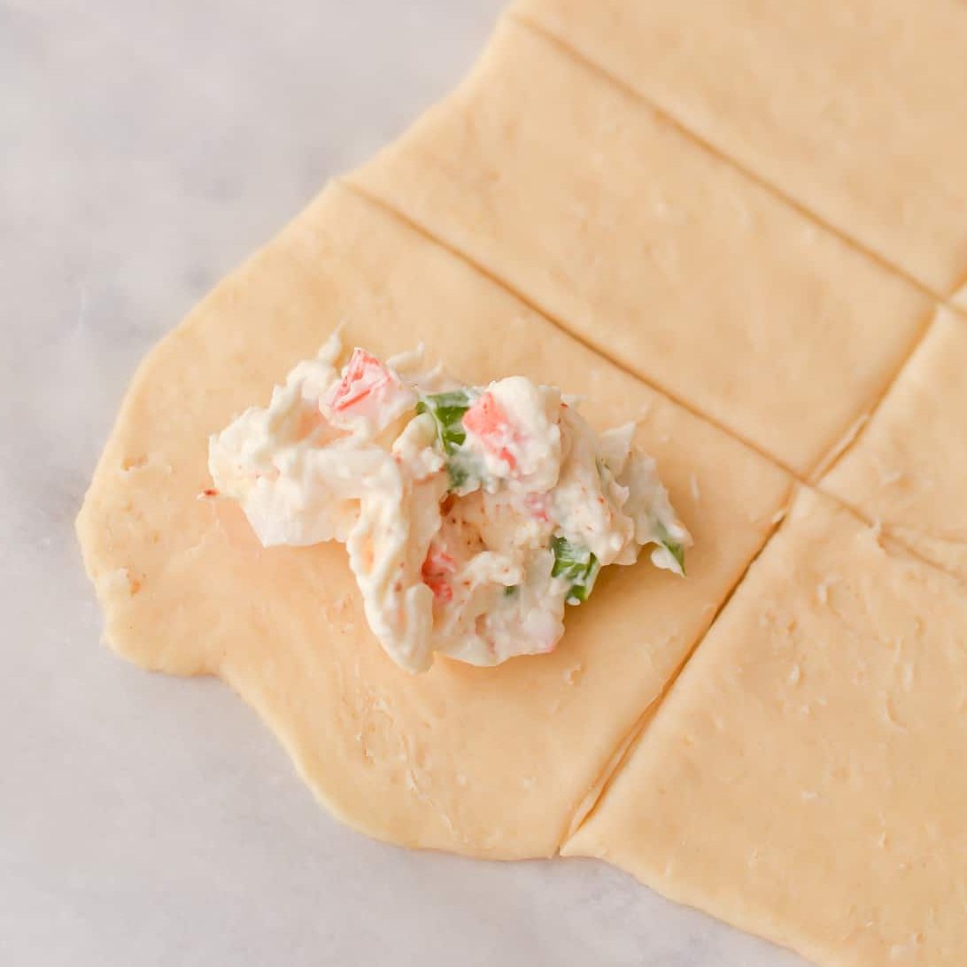 Place a bit of the filling in the center of each square of dough.