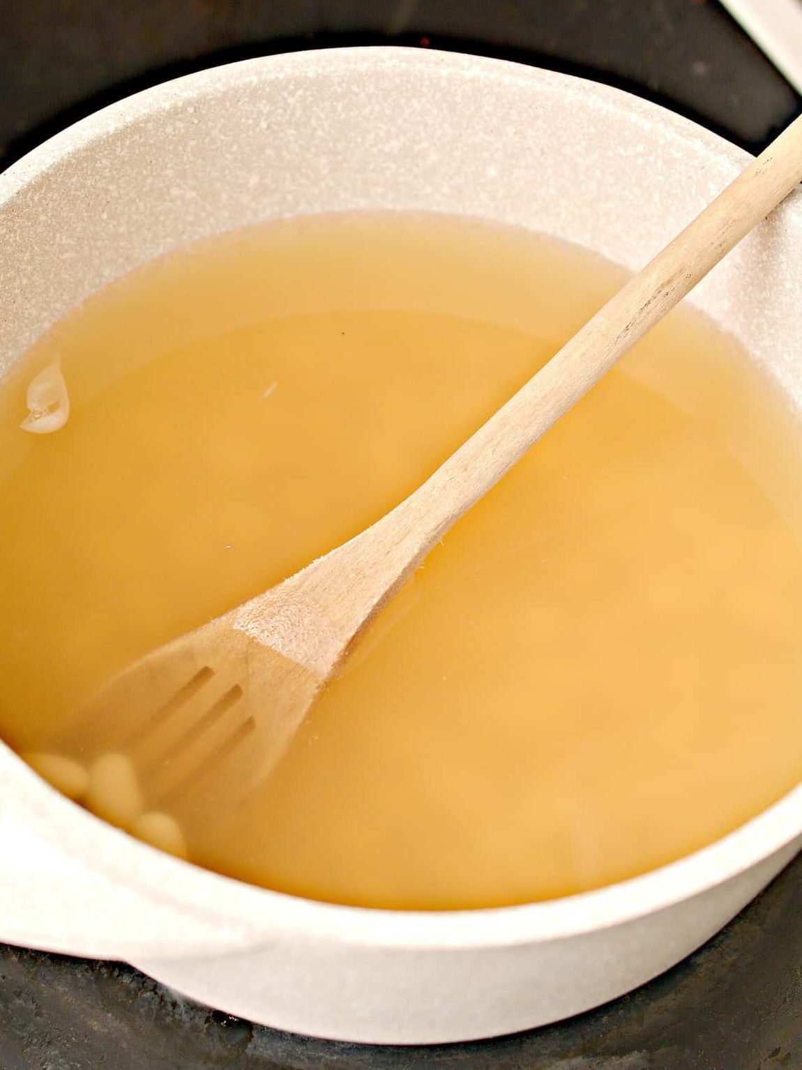 In a pot over medium-high heat on the stove, bring the chicken broth and can of beans to a boil.