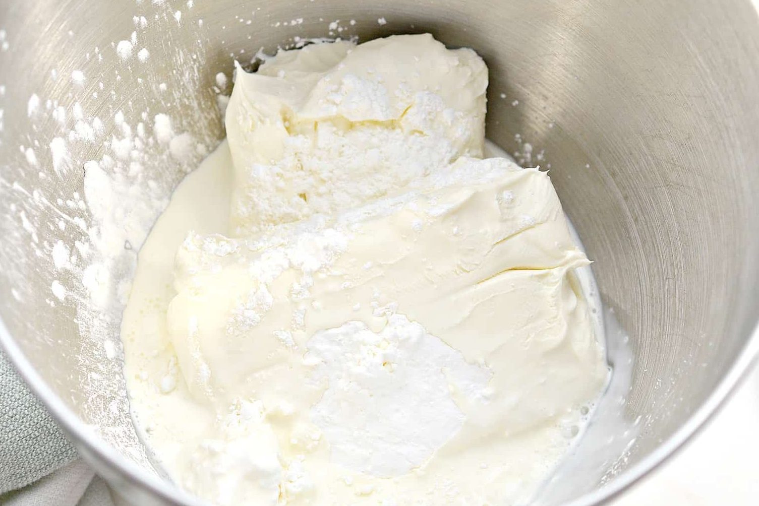 Place 16 oz of cream cheese, ¼ cup of cornstarch, and ½ cup of heavy whipping cream into a mixing bowl.