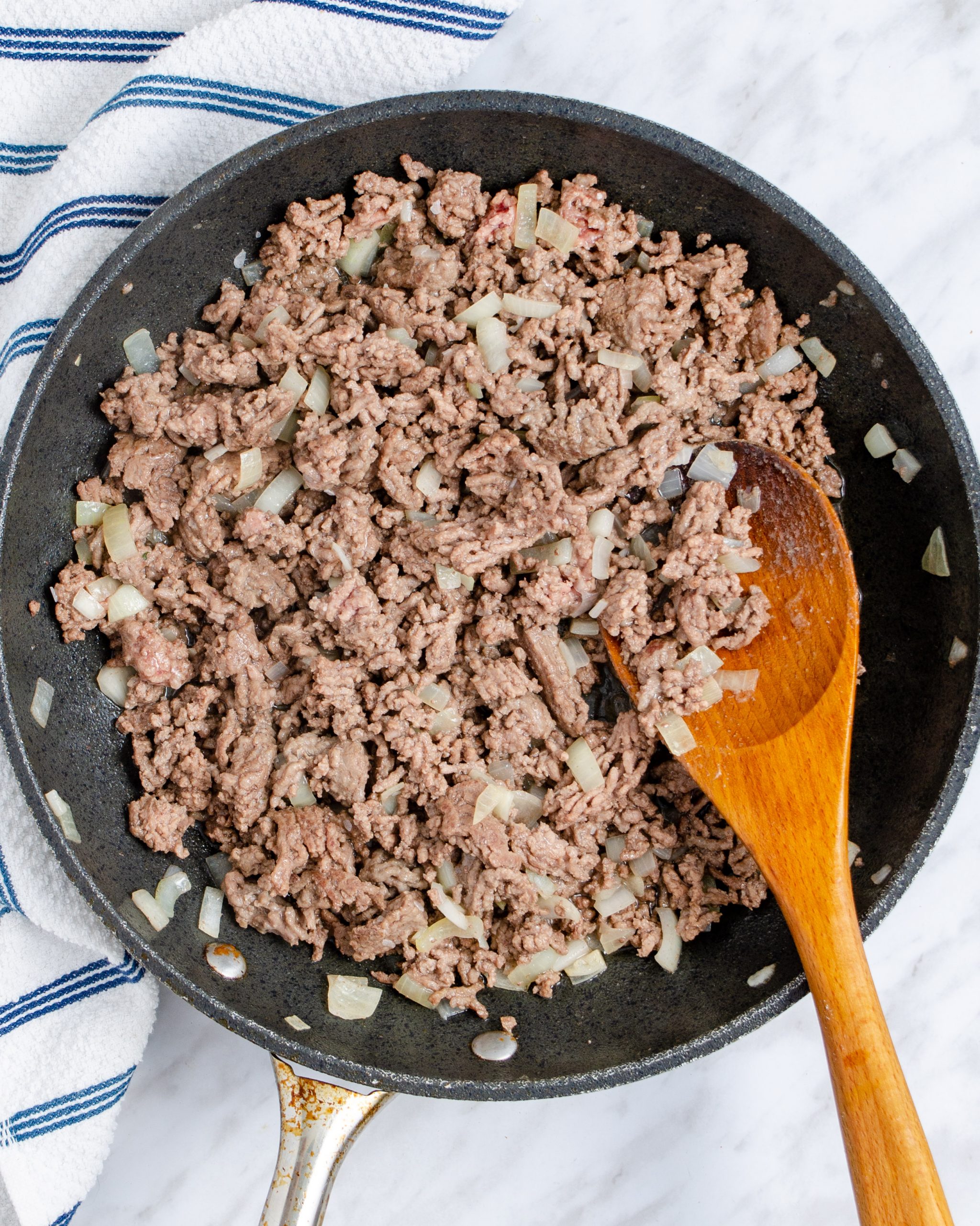 Add the ground beef and onion to the skillet and saute until the meat is completely browned and the onion has softened.