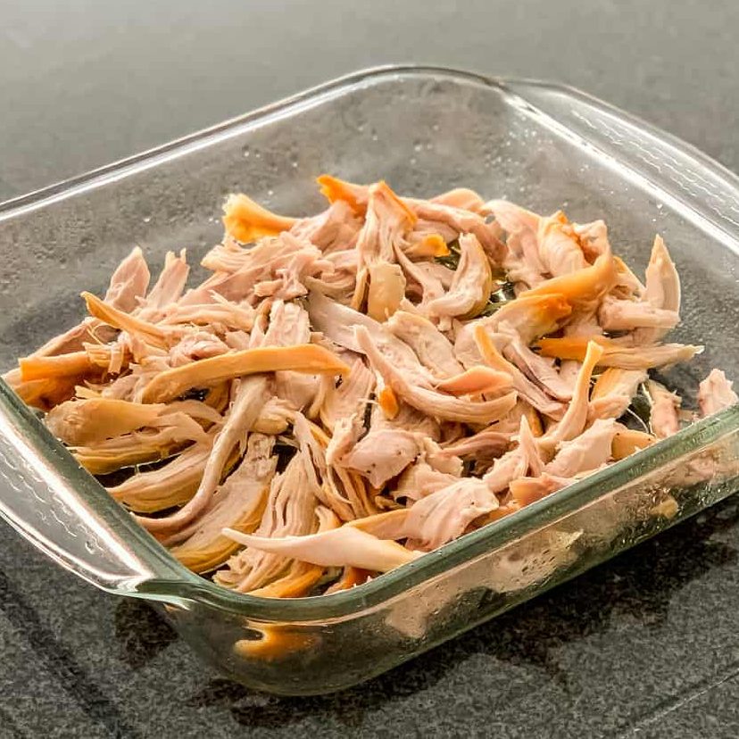 In the baking dish, spread shredded chicken into the bottom.