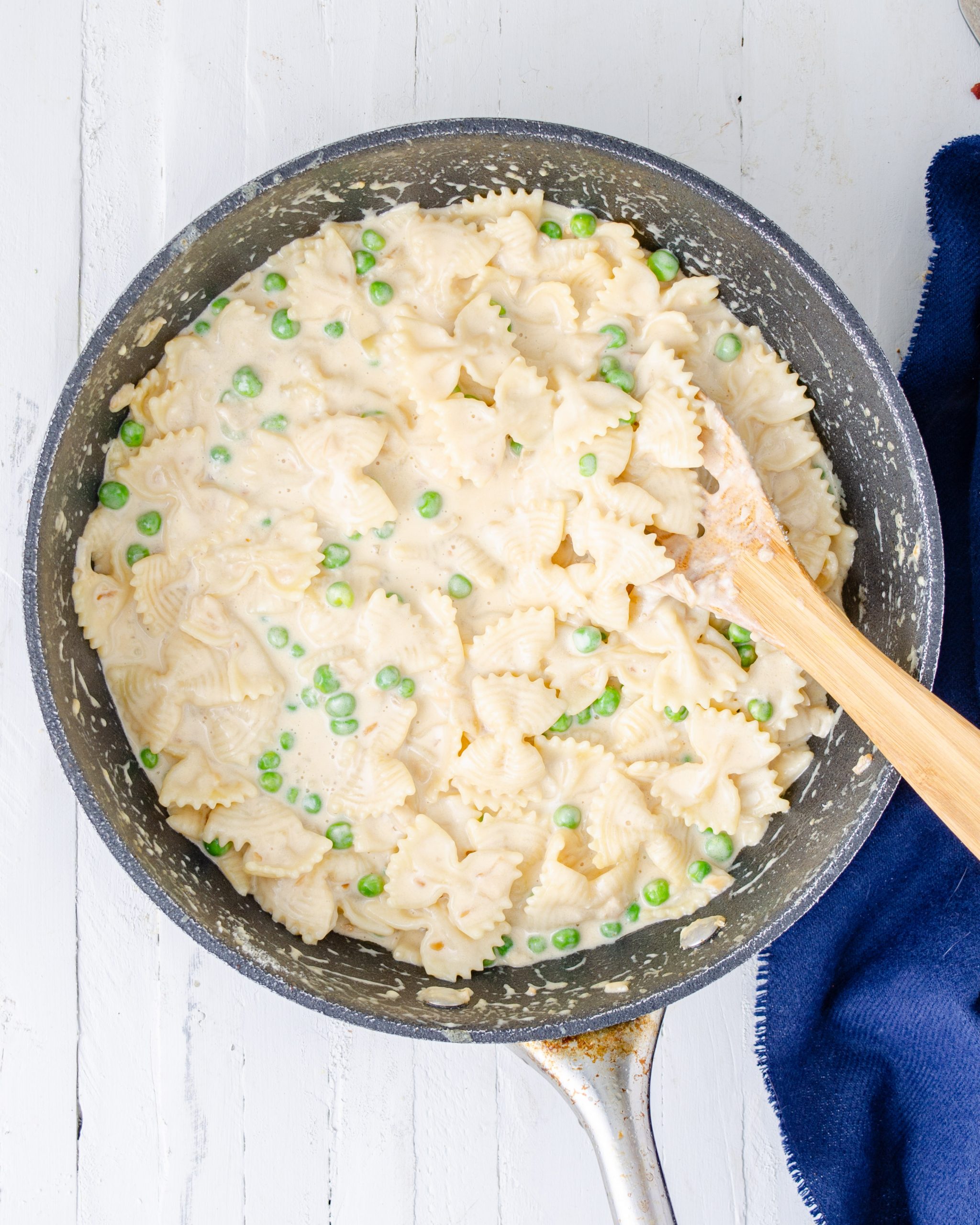 Place the pasta, parmesan cheese, and peas into the skillet with the sauce, and stir to coat well. 
