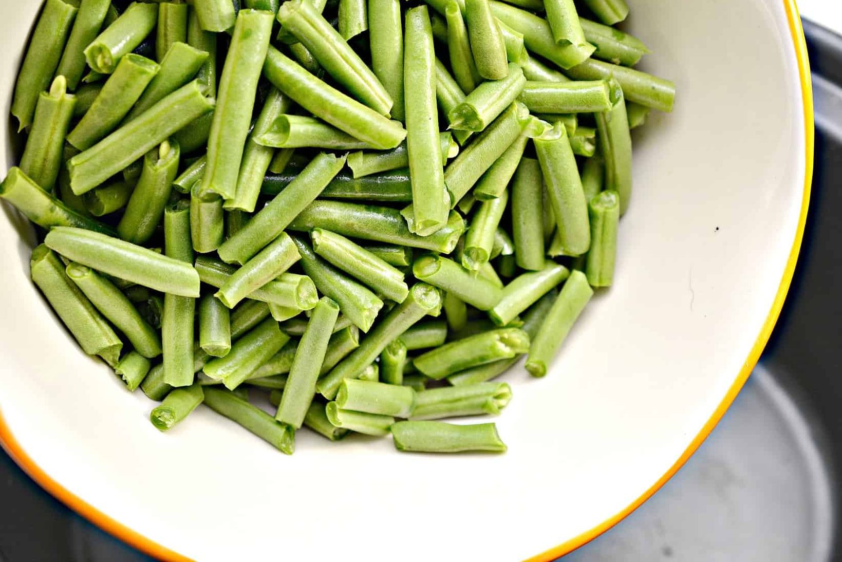 Start by adding 2 lbs of fresh green beans snapped and cut into pieces into a slow cooker.