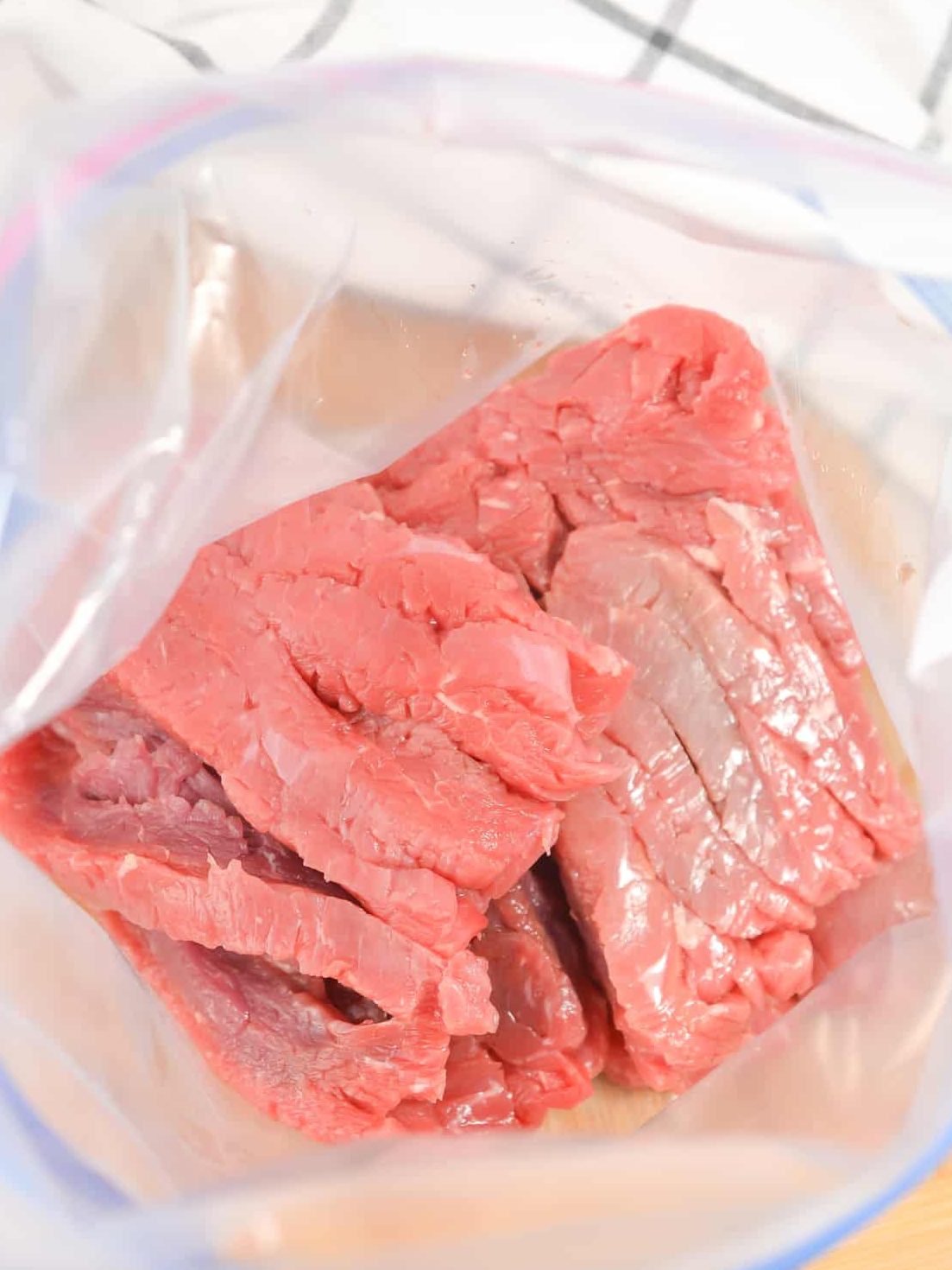 Add the steak slices to a Ziploc bag.