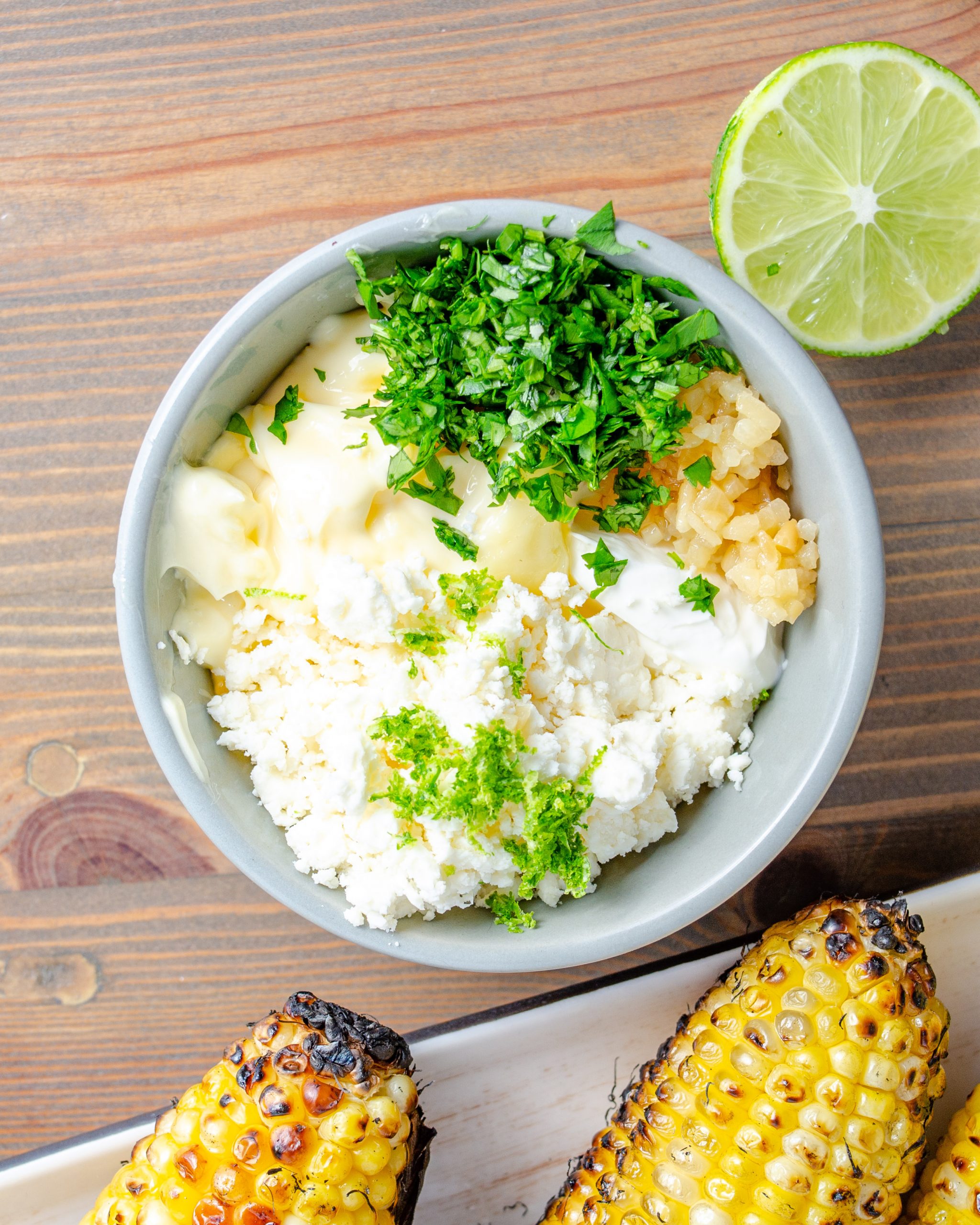 In a small bowl, mix together sour cream, mayonnaise, cotija cheese, garlic, lime zest and juice, and cilantro.