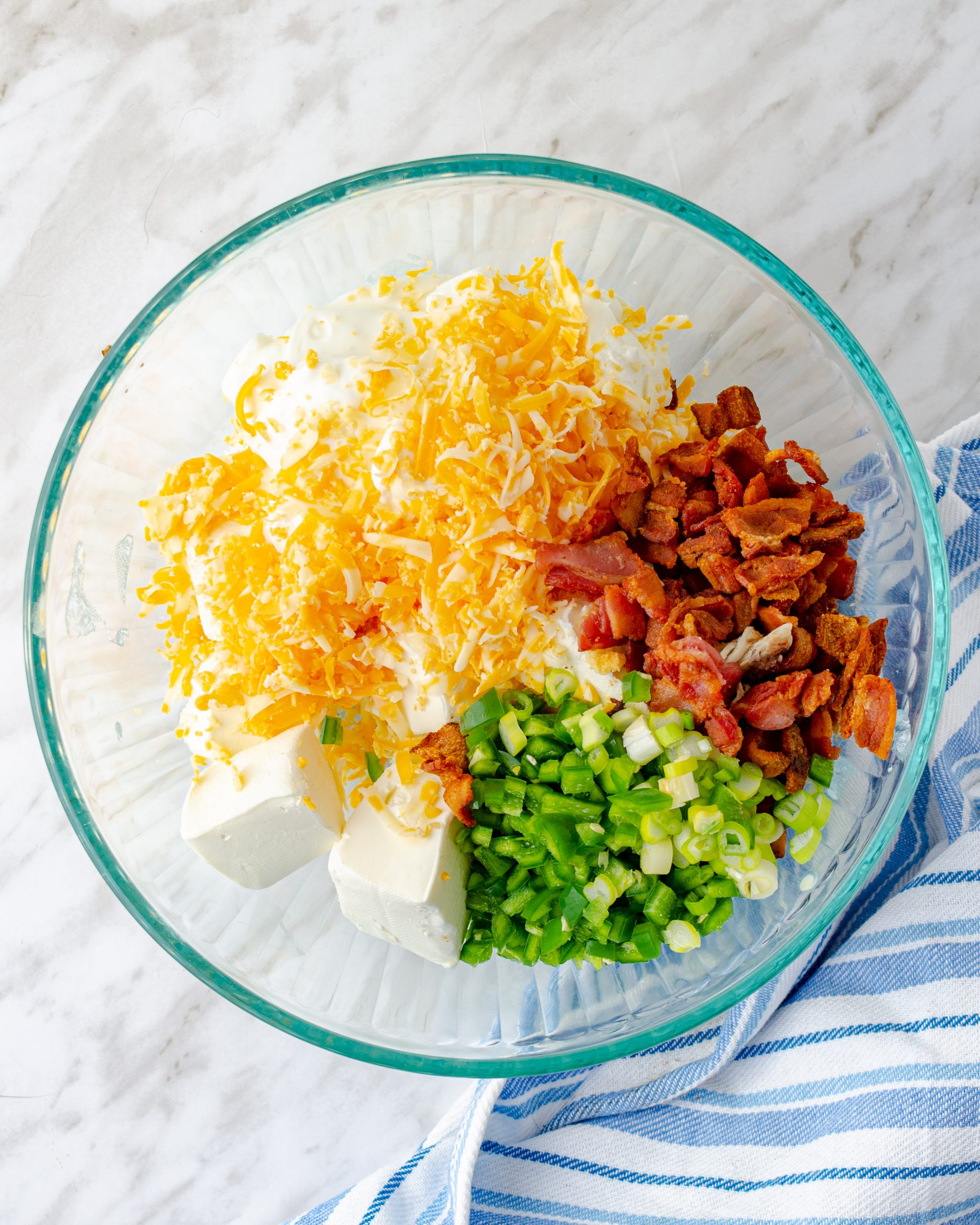 Combine the sour cream, ¾ of the bacon pieces, 1 ½ cups of the cheese, ½ of the green onions, and the Jalapeno peppers in a mixing bowl. Stir to mix well. 