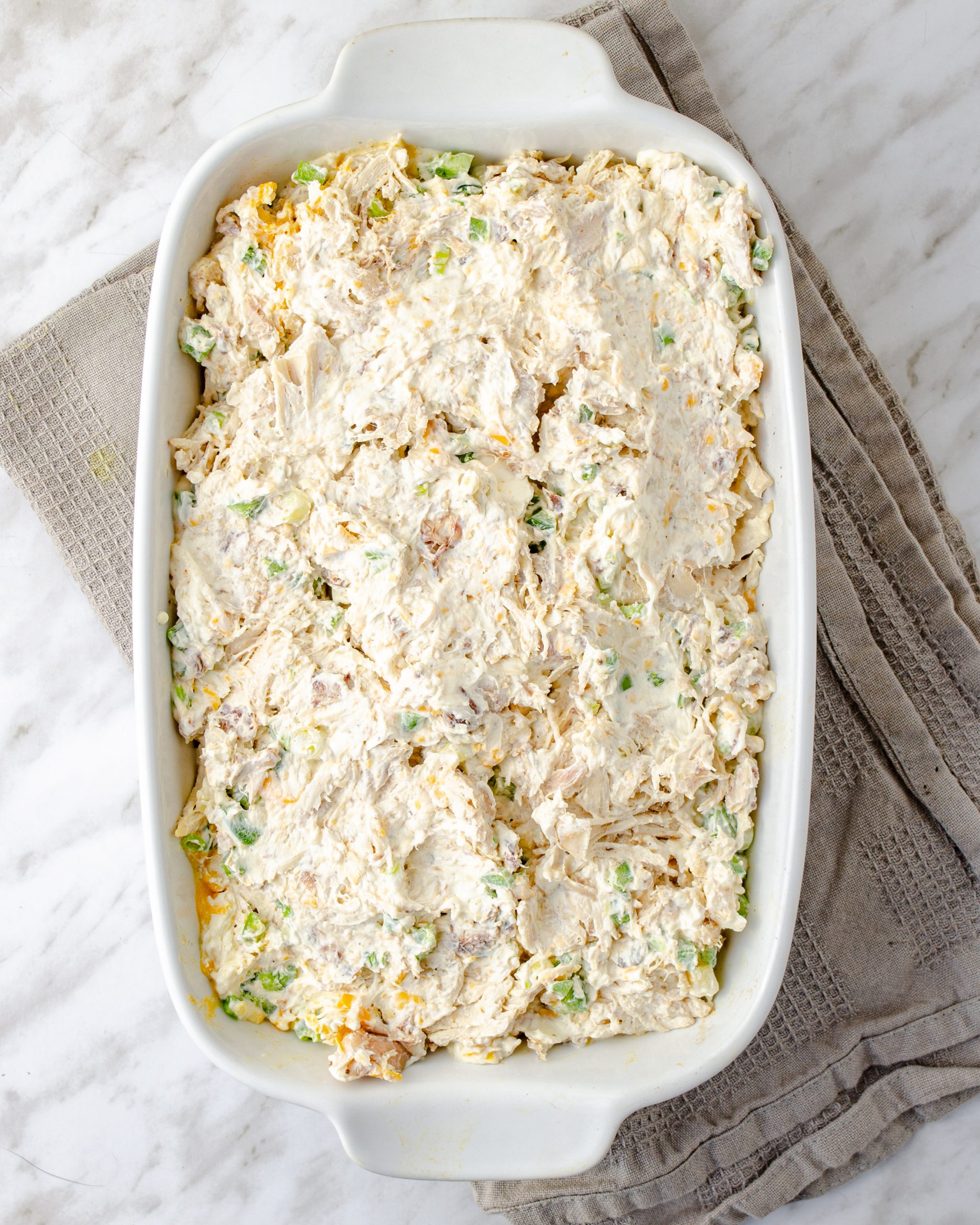 Spread the mixture over the tater tots, and sprinkle with the remaining cheese, green onions, and bacon.