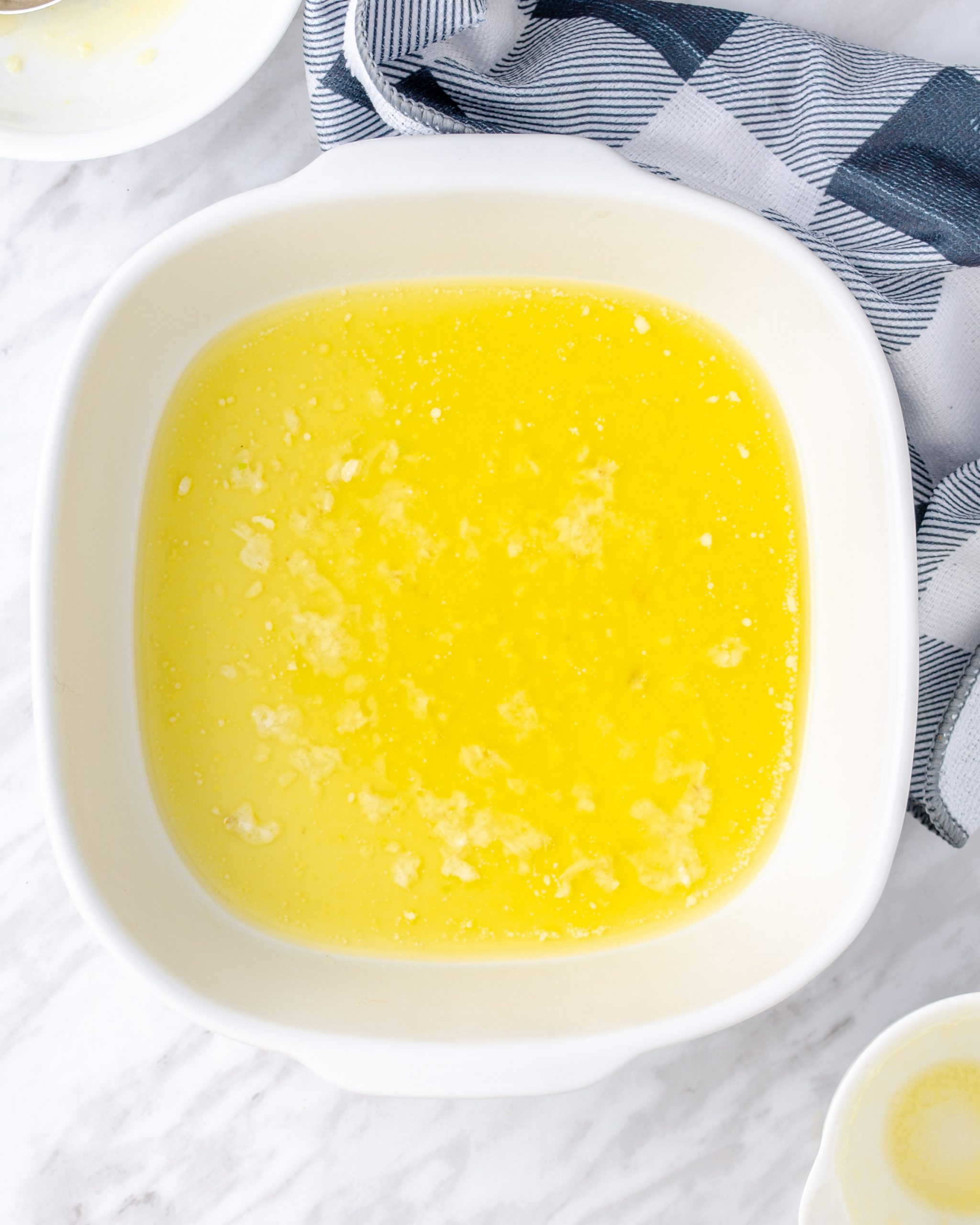 In a small bowl, mix the melted butter with minced garlic, and pour into a 9×111 inch glass casserole dish, spreading it all over the bottom of the dish.
