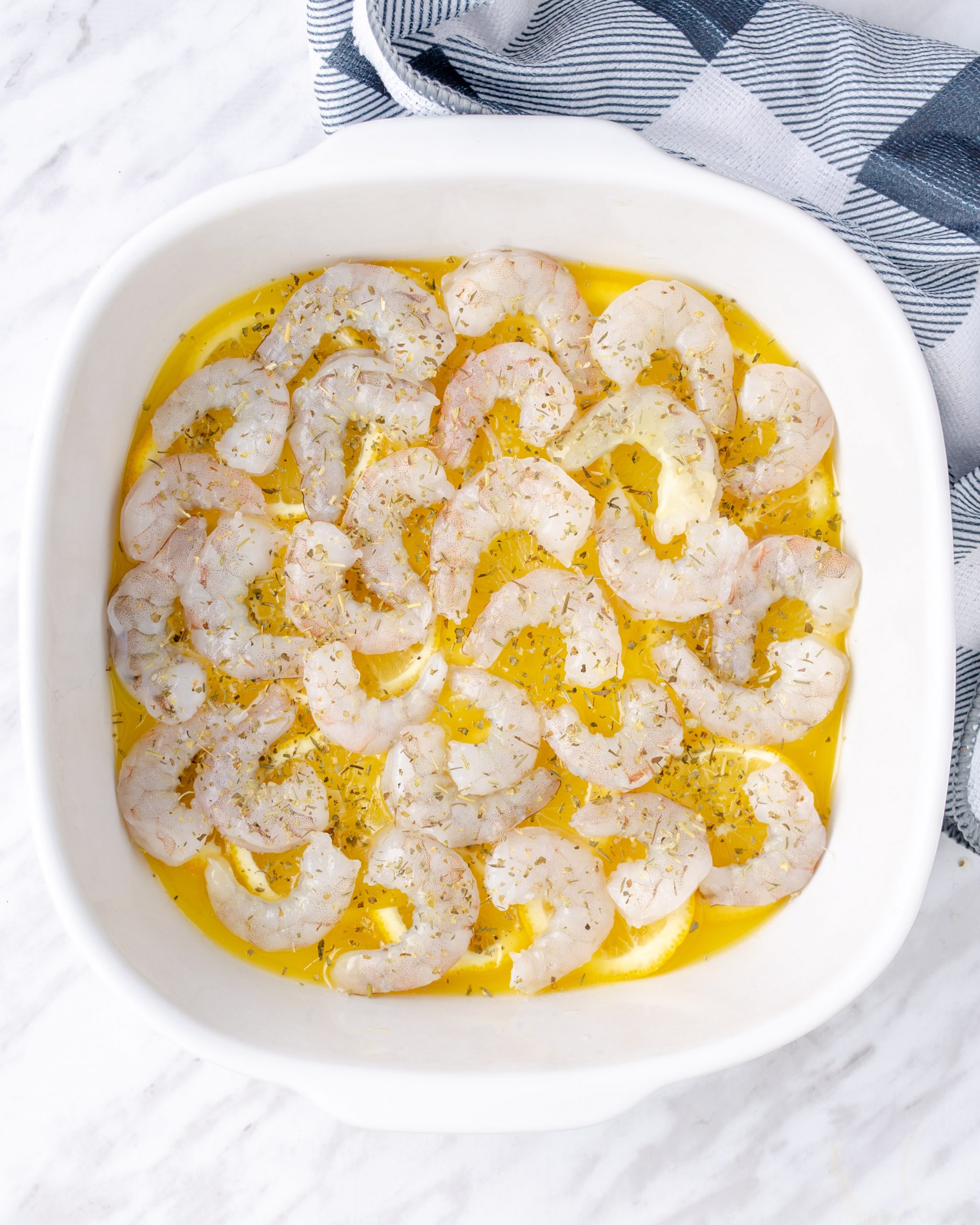 Arrange the cleaned and deveined shrimp on top of the lemon slices.