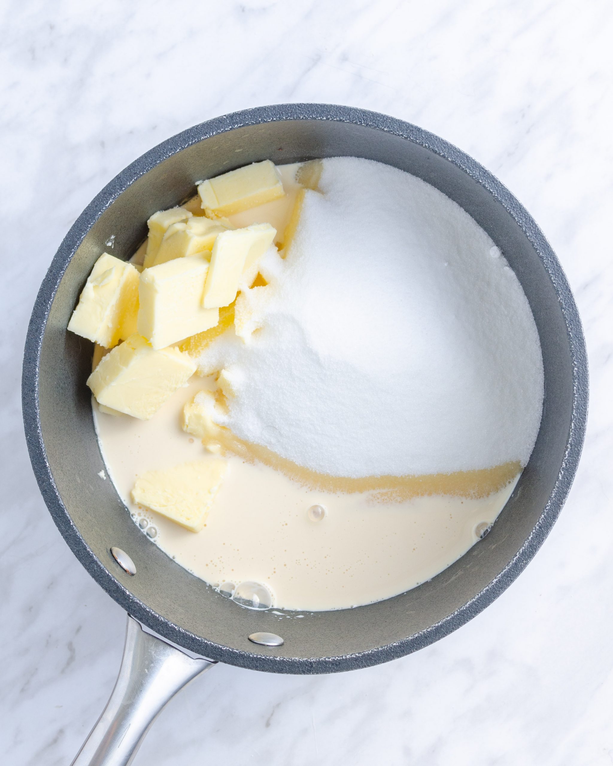 Place the butter, sugar, and milk into a saucepan over high heat on the stove, and bring to a boil, whisking often to combine.