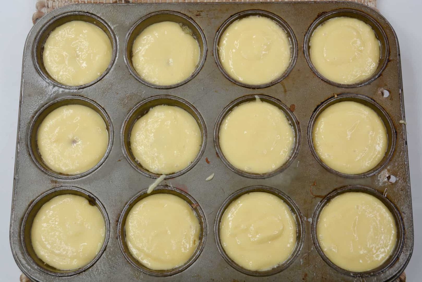 Scoop the prepared cake batter into each of the muffin wells. Fill just below the top of the muffin well. (Do not overfill.)