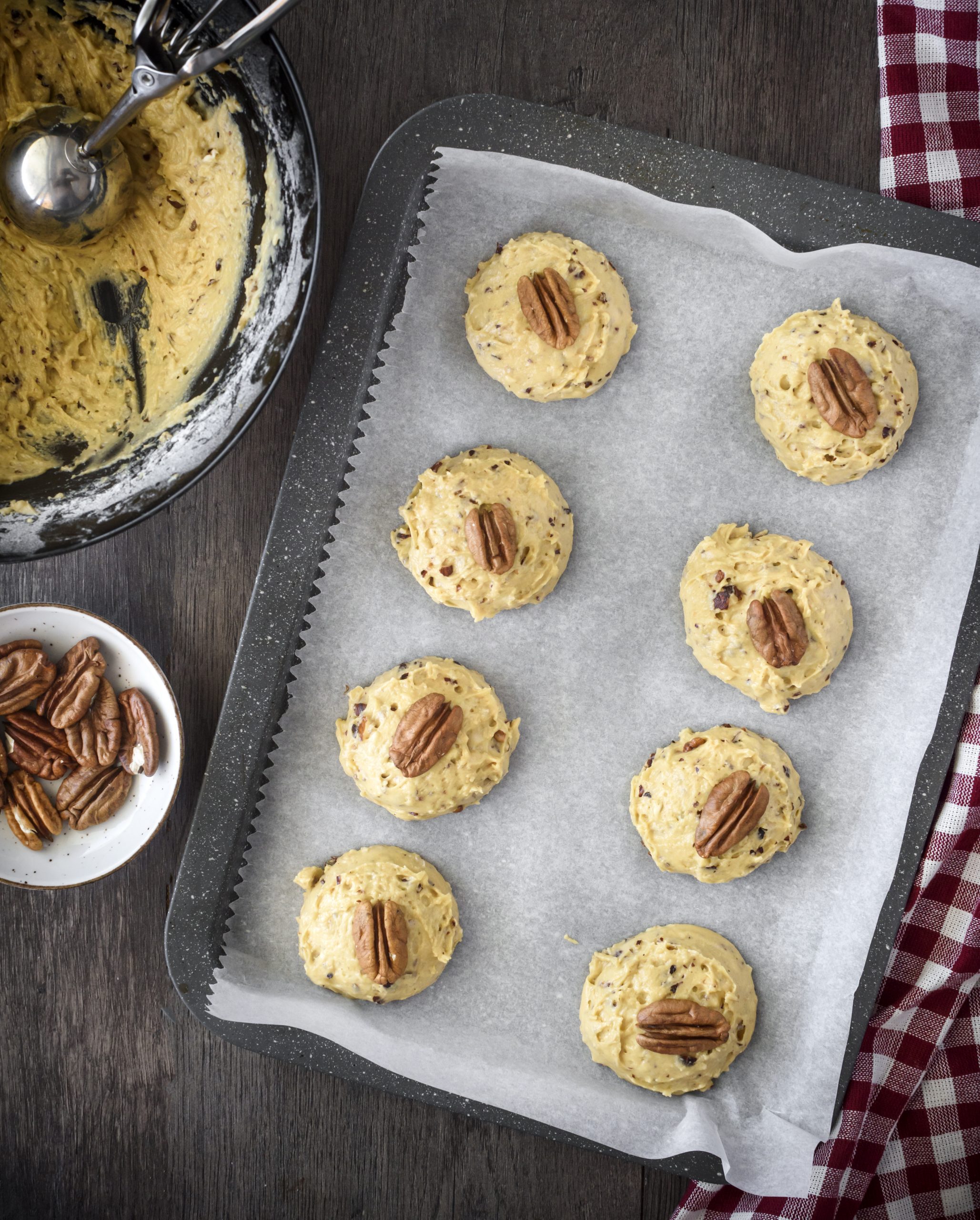 Place the cookies onto a parchment-lined baking sheet, and top each one with a pecan half. 
