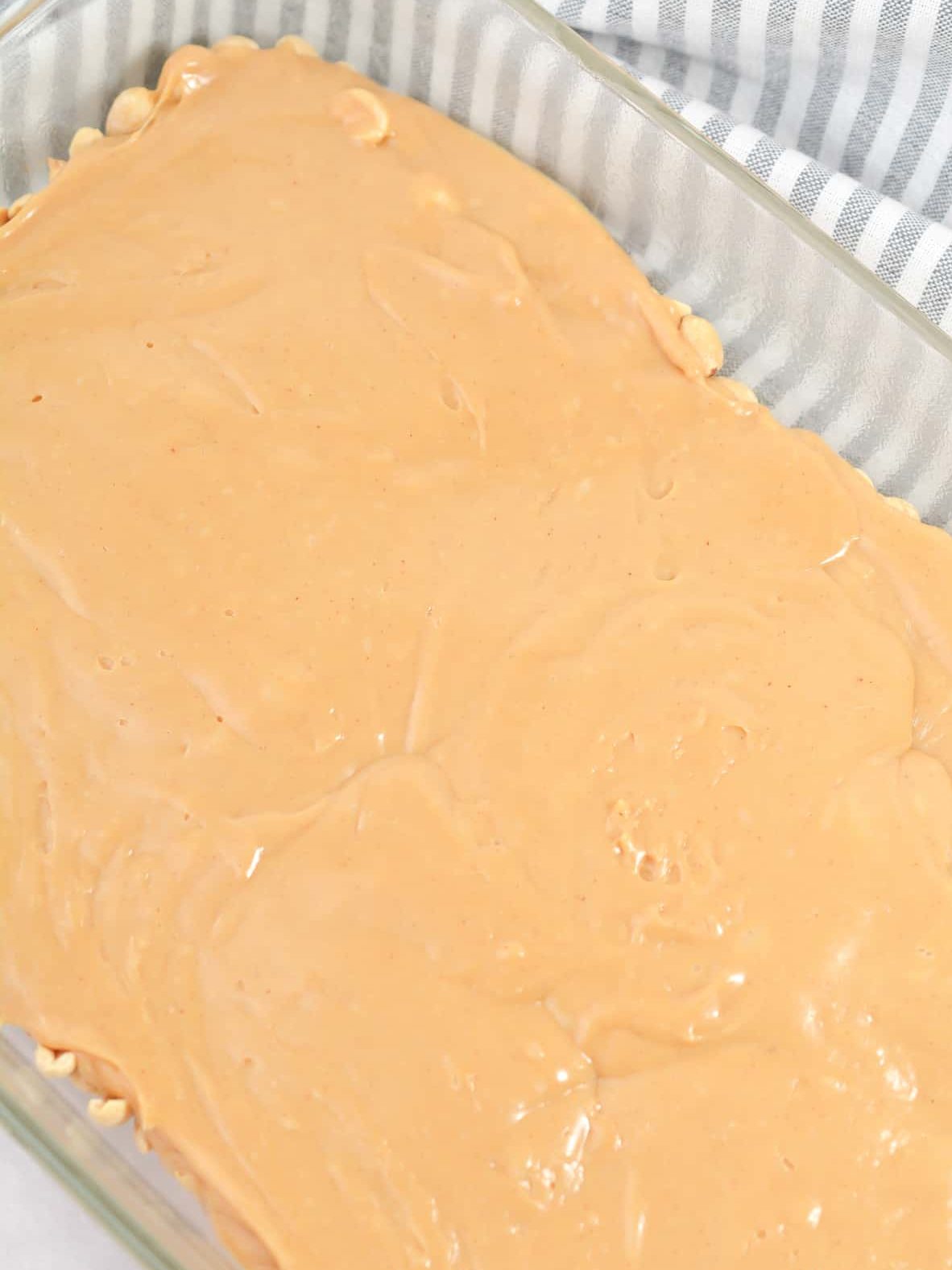 Pour the peanut butter chip mixture over the top of the peanuts in the baking dish, and smooth into an even layer.