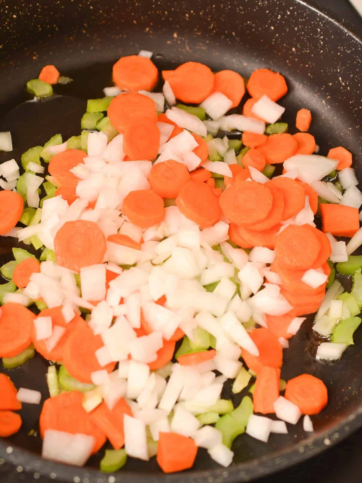 Add the onions, celery, and carrots to the olive oil in a skillet over medium heat.