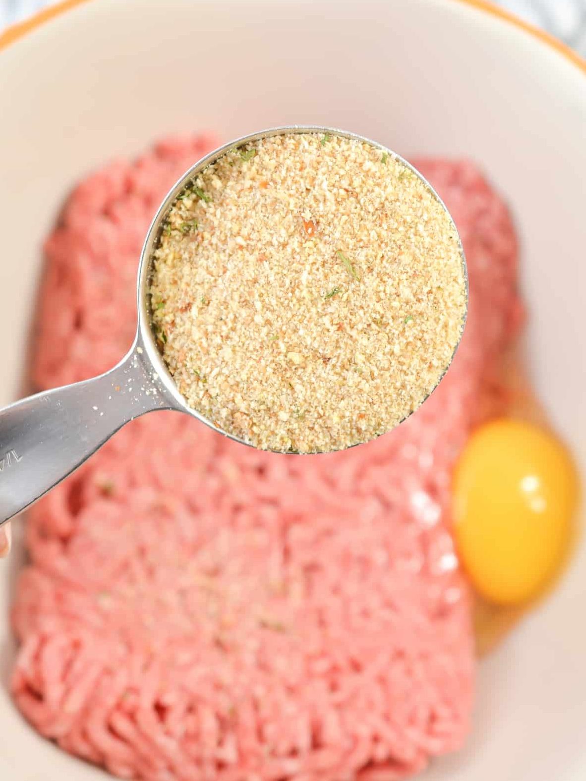 In a bowl, combine 1 lb of ground beef, ¼ cup of breadcrumbs, and 1 large egg.