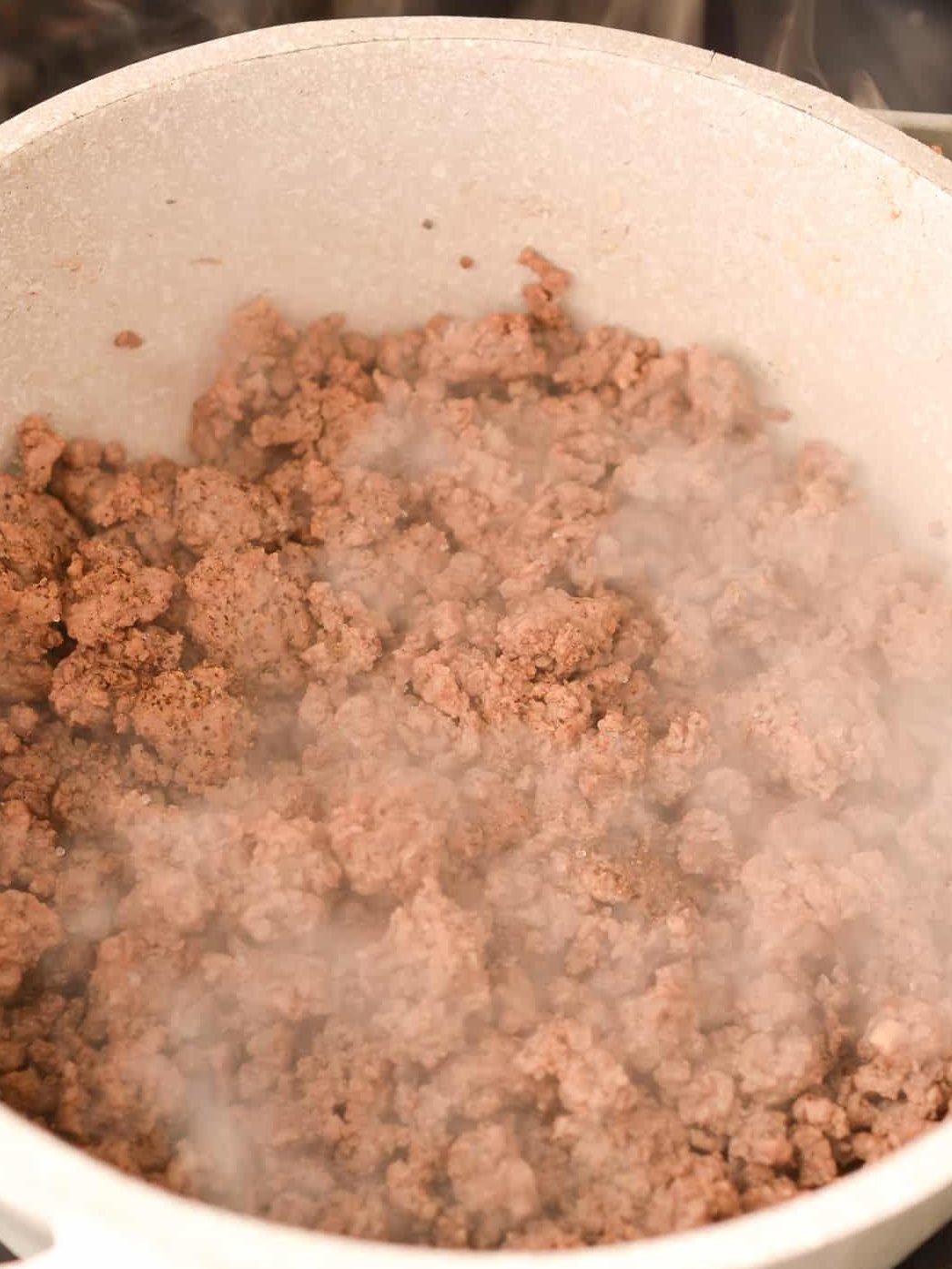Brown 1 lb of ground beef and 1 onion in a large pot over medium-high heat.
