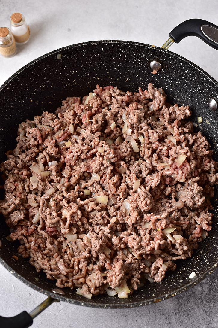 Add the olive oil, ground beef, and onions to a skillet over medium-high heat.